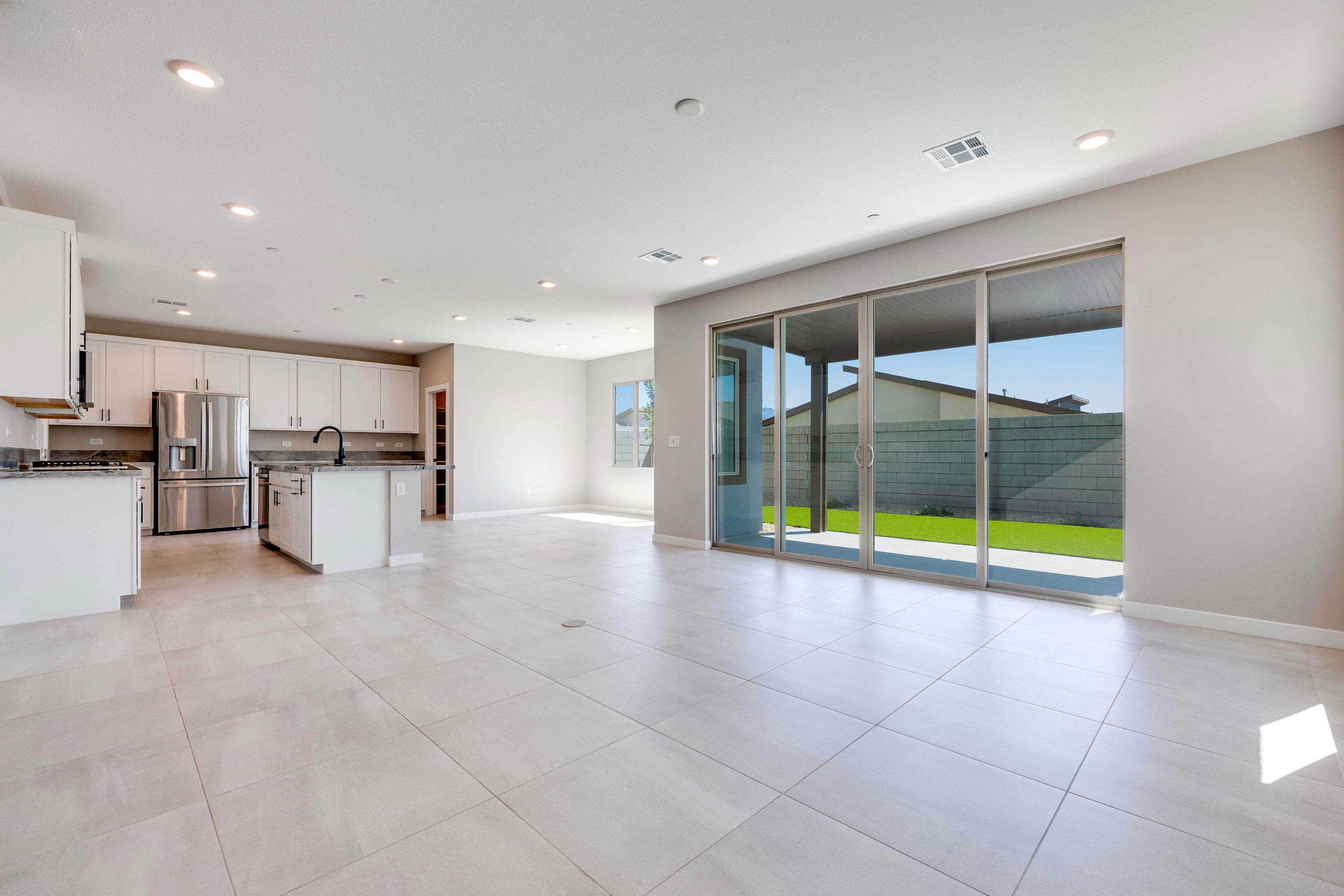A spacious, modern kitchen and living area with large sliding glass doors opening to a green backyard.