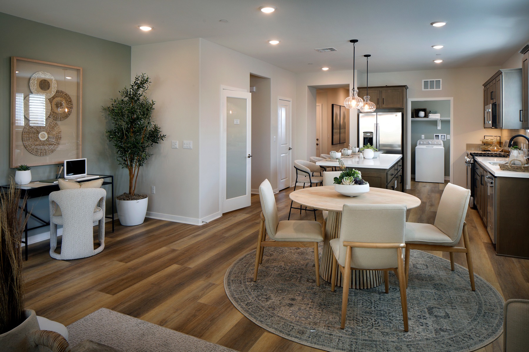 A cozy and inviting open-concept living space with a dining area, kitchen, and living room, featuring hardwood floors, neutral-toned walls, and a mix of modern and rustic decor elements.