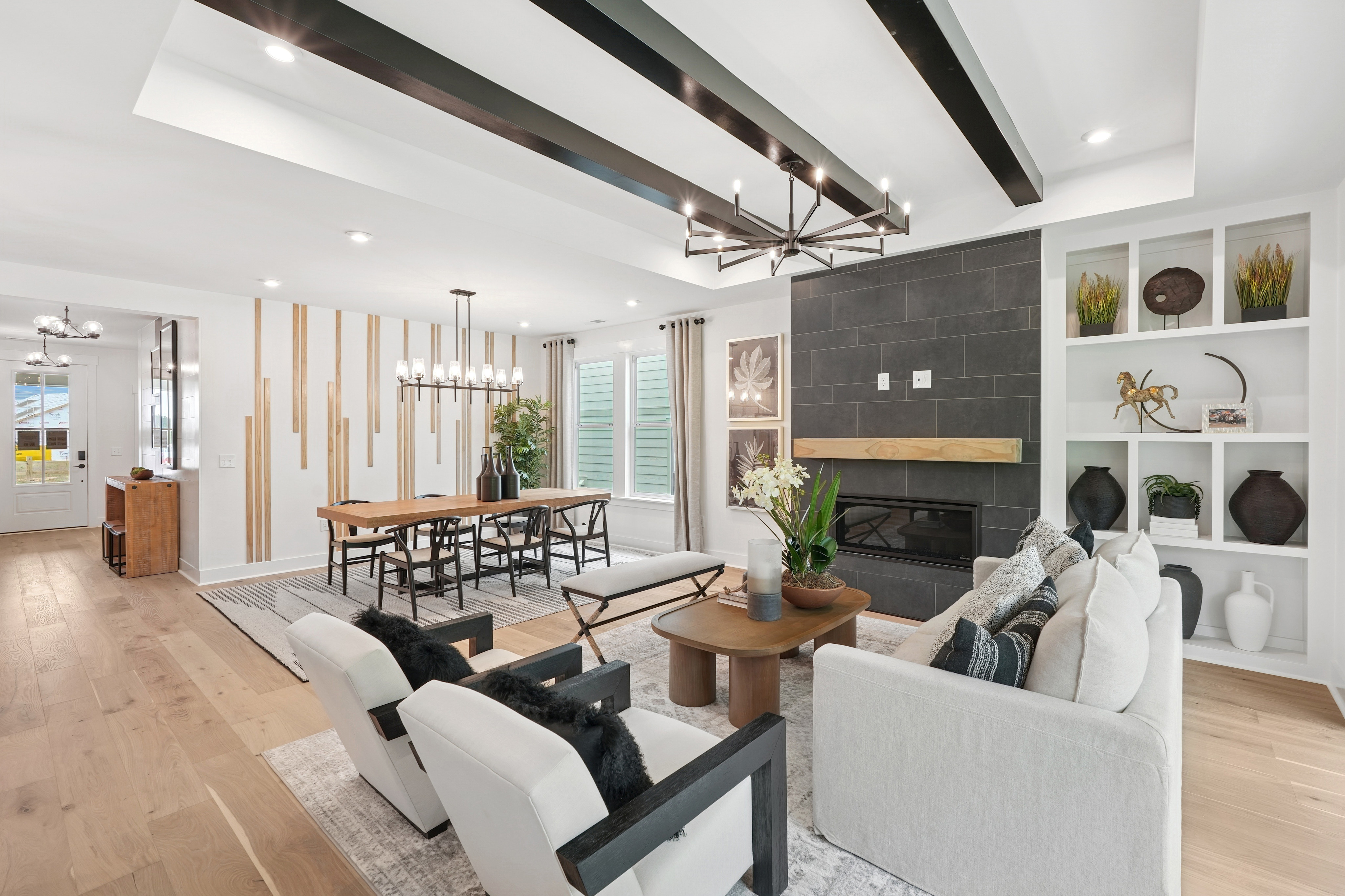 A modern and stylish living room with a fireplace, wooden beams on the ceiling, and a mix of contemporary and rustic furniture and decor elements.