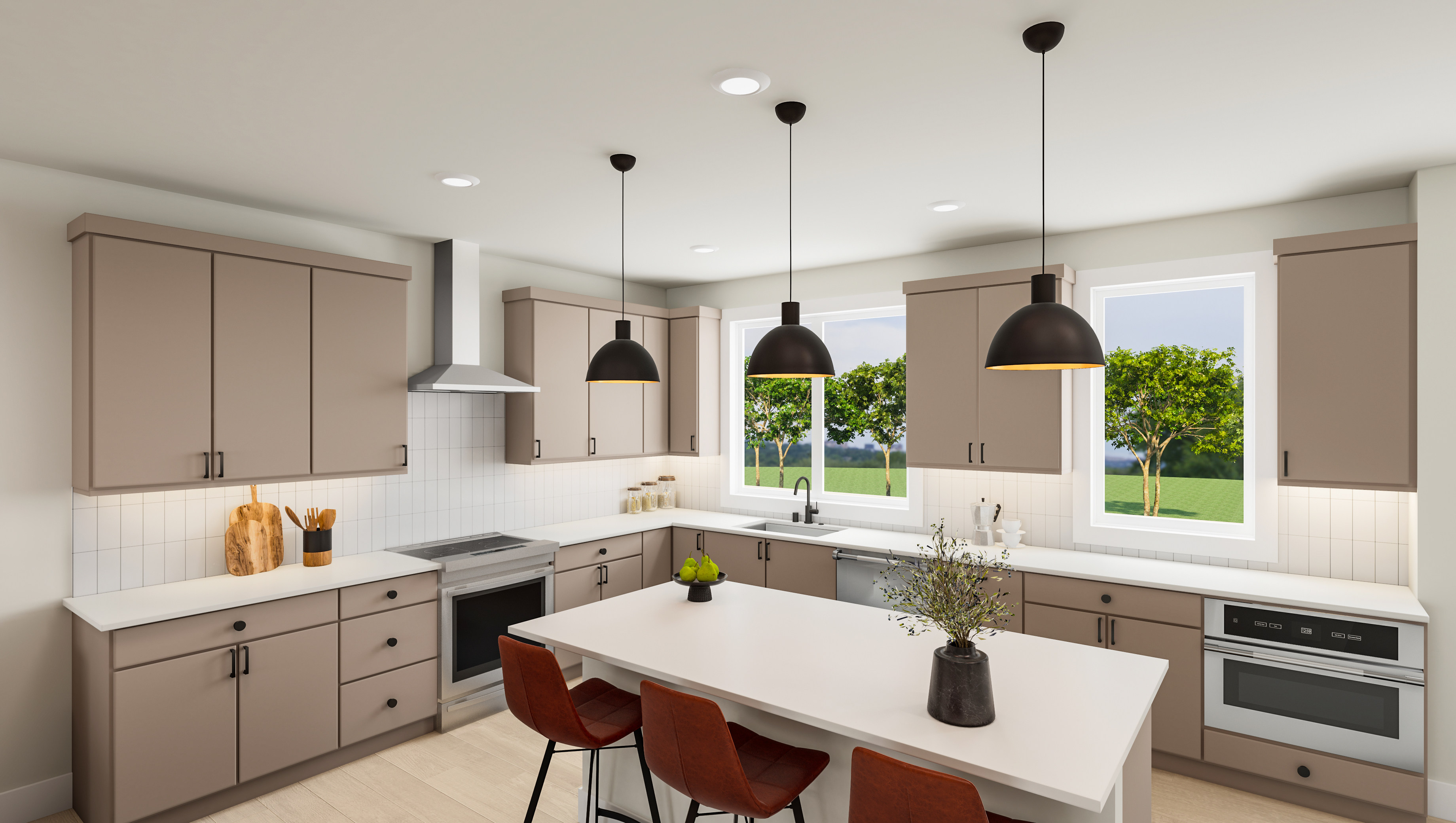 A modern, well-lit kitchen with beige cabinets, a white countertop, and pendant lights hanging above a central island. The kitchen overlooks a grassy outdoor area through large windows.