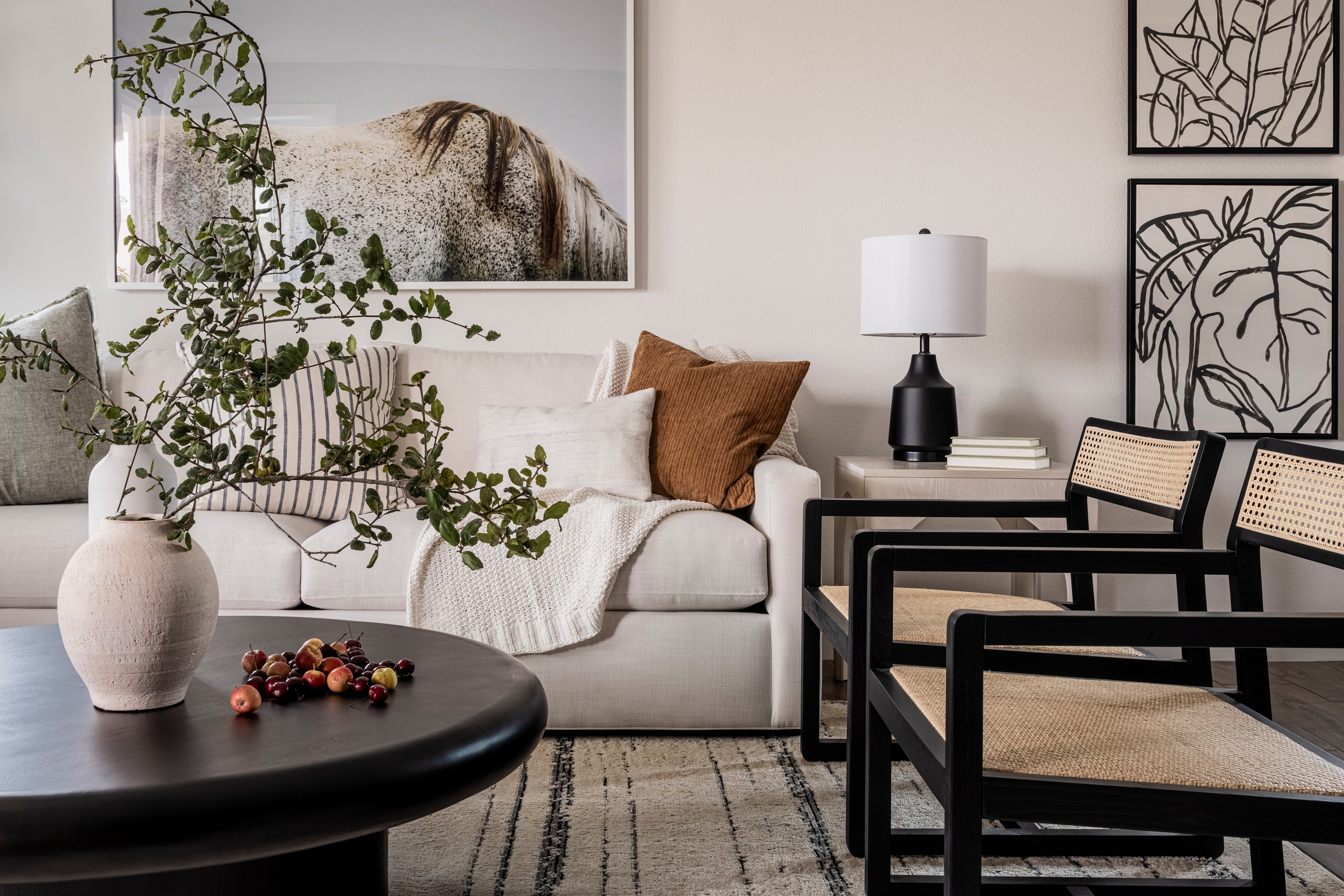 A cozy and stylish living room with a large sofa, a round coffee table, and various decorative elements, including a framed landscape artwork on the wall.