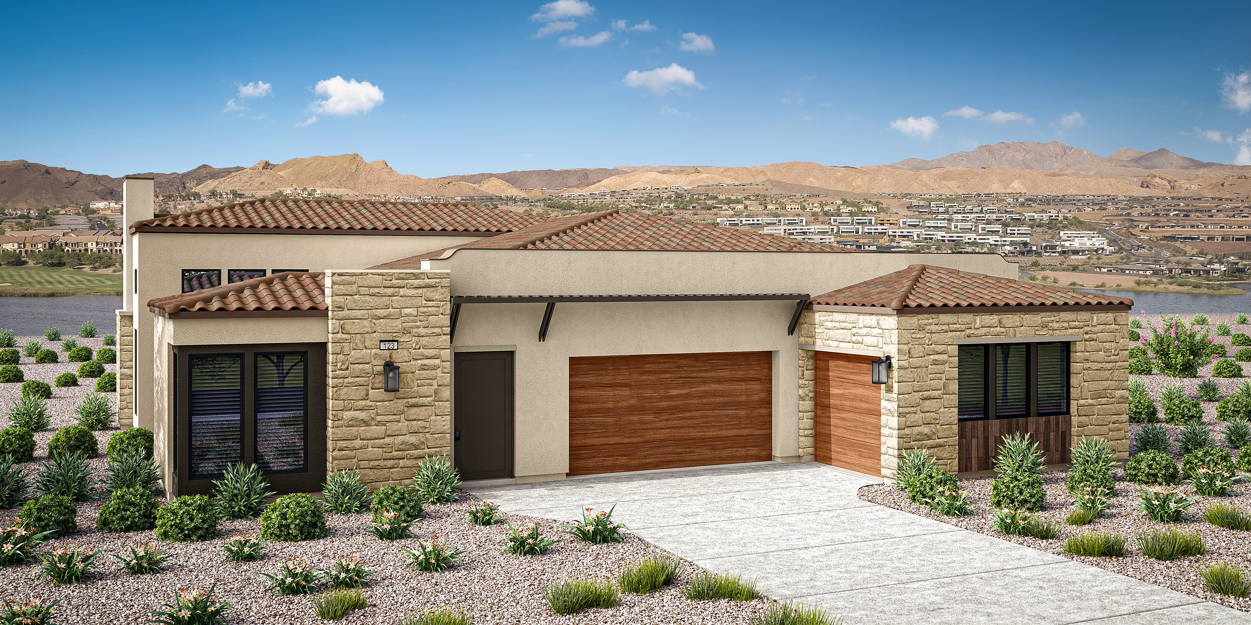 A modern, single-story house with a tiled roof and a wooden garage door sits in the foreground, surrounded by landscaped gardens. In the background, a mountainous desert landscape can be seen under a clear blue sky with scattered clouds.