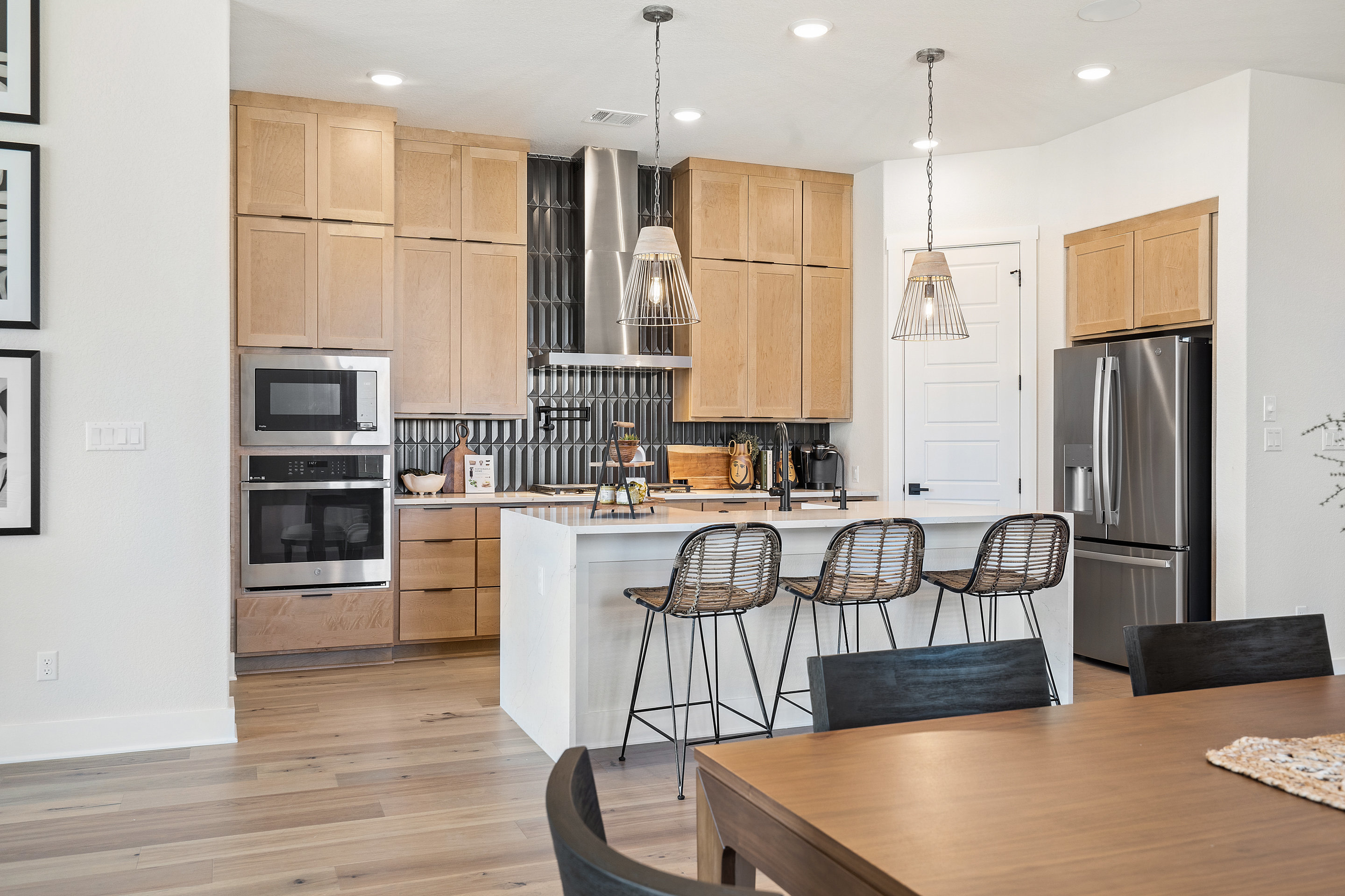 A modern and minimalist kitchen with wooden cabinets, stainless steel appliances, and a dining area with a wooden table and chairs.