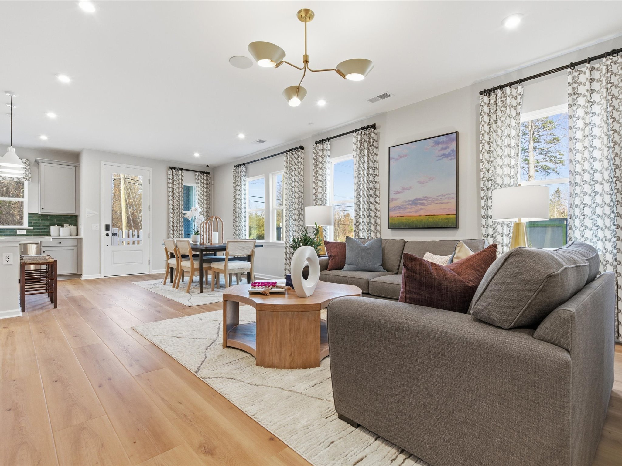 A modern and spacious living room with a comfortable gray sofa, a wooden coffee table, and a large window overlooking a scenic landscape.