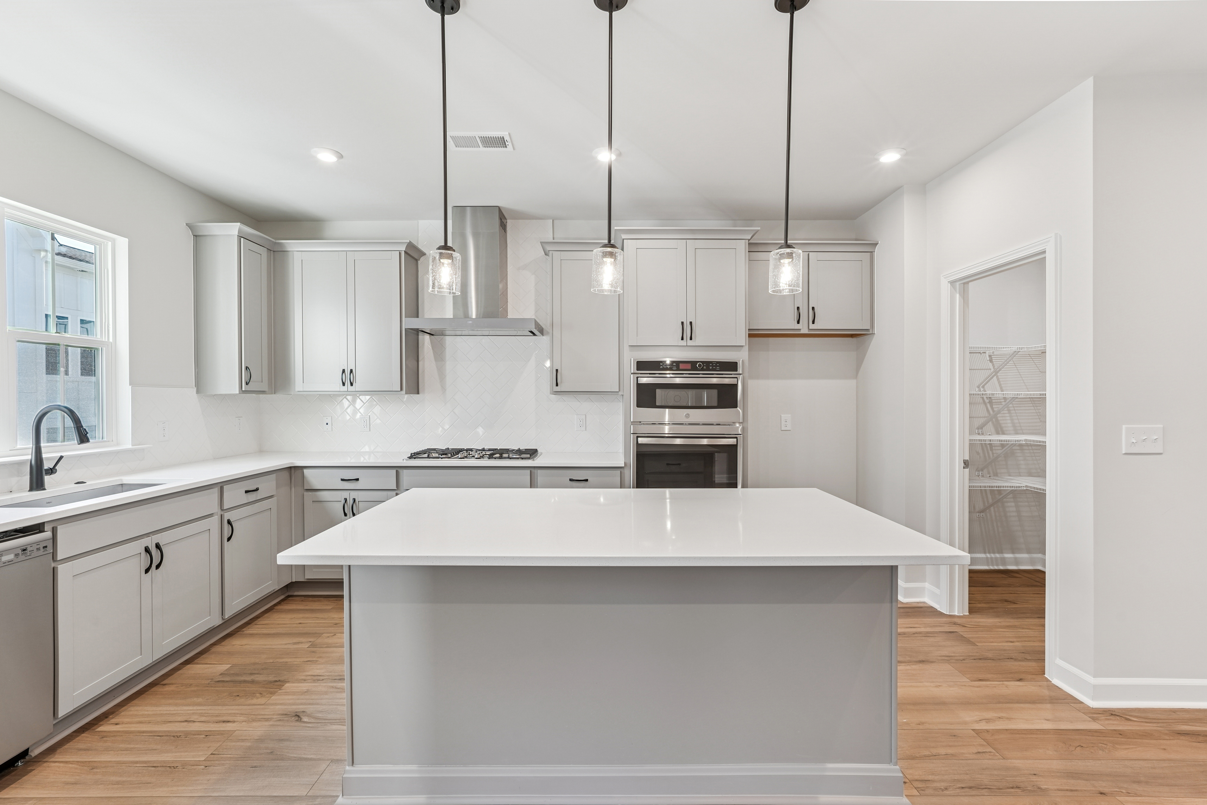 A modern, bright, and spacious kitchen with white cabinets, a large island, and pendant lighting fixtures.
