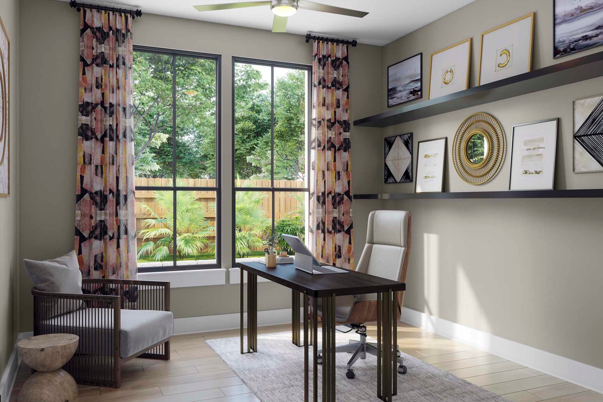 A cozy home office space with a large window overlooking a lush, green outdoor area, featuring a desk, chair, and various decorative elements on the walls.