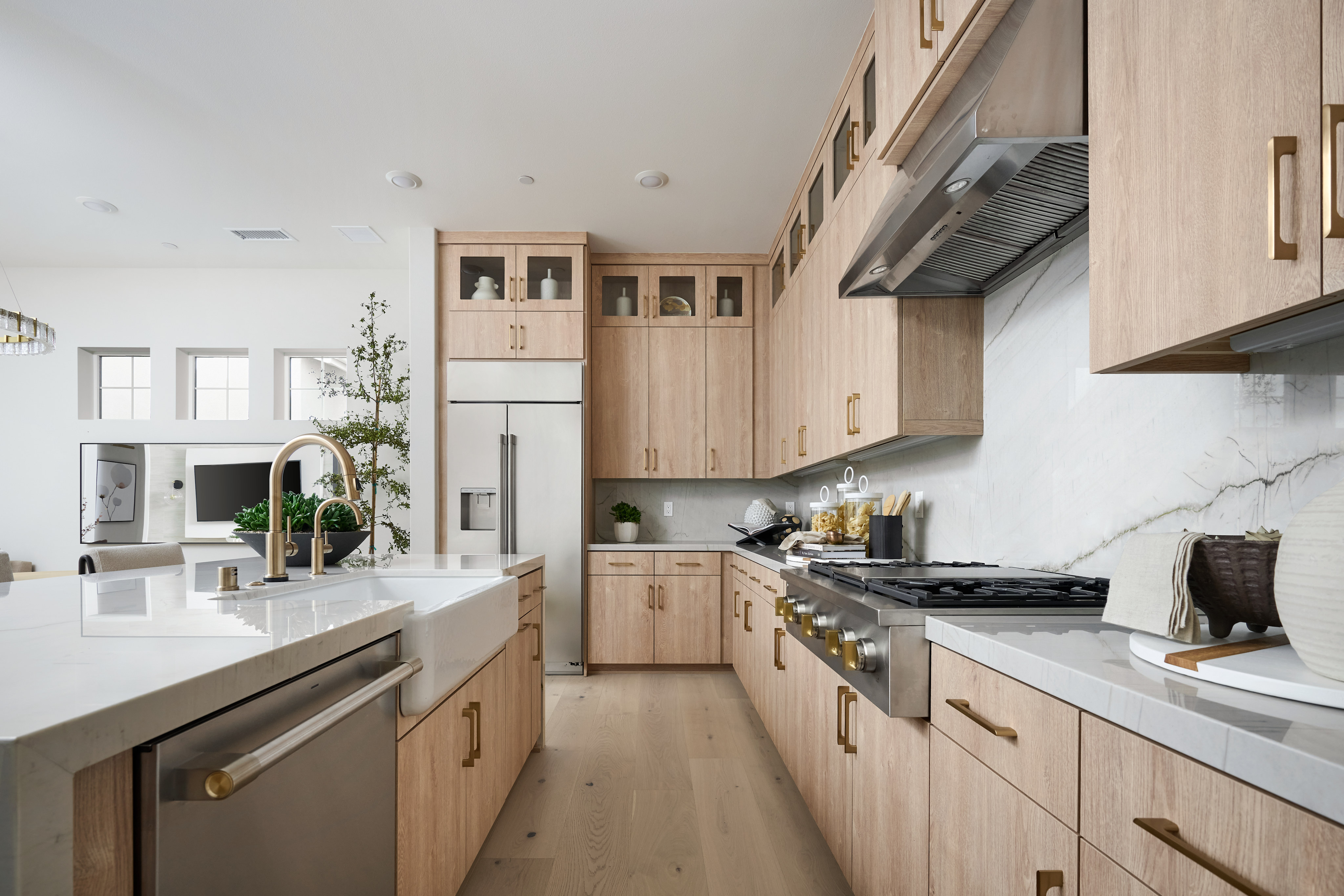 A modern, minimalist kitchen with light wood cabinetry, stainless steel appliances, and a marble countertop, creating a sleek and stylish atmosphere.