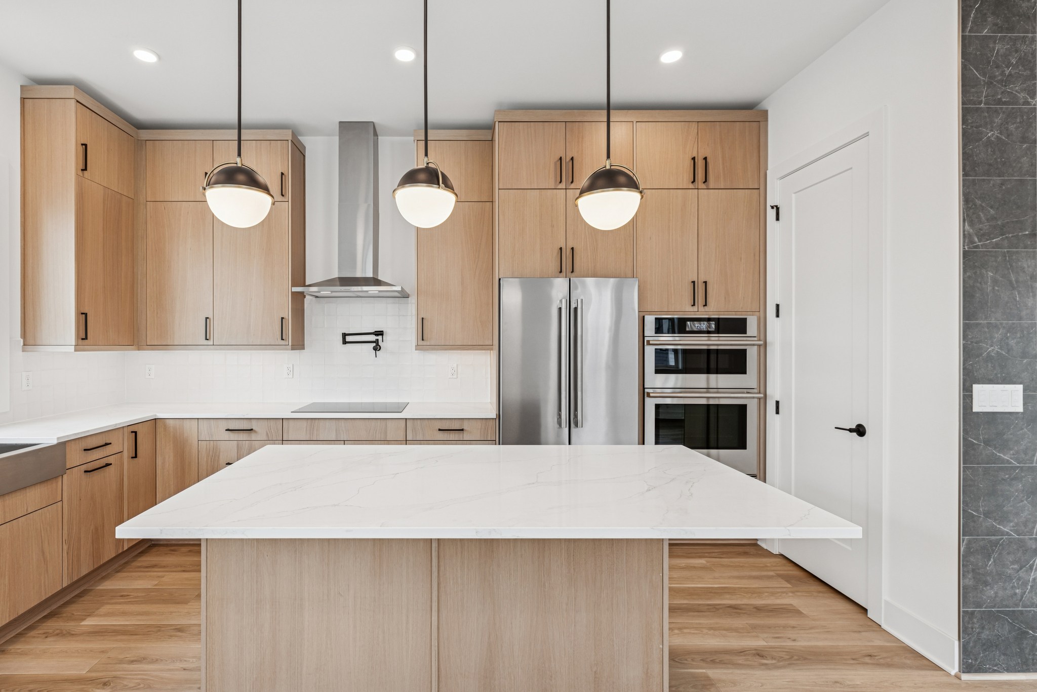 A modern, well-equipped kitchen with light-colored wood cabinets, a large island countertop, and stainless steel appliances.