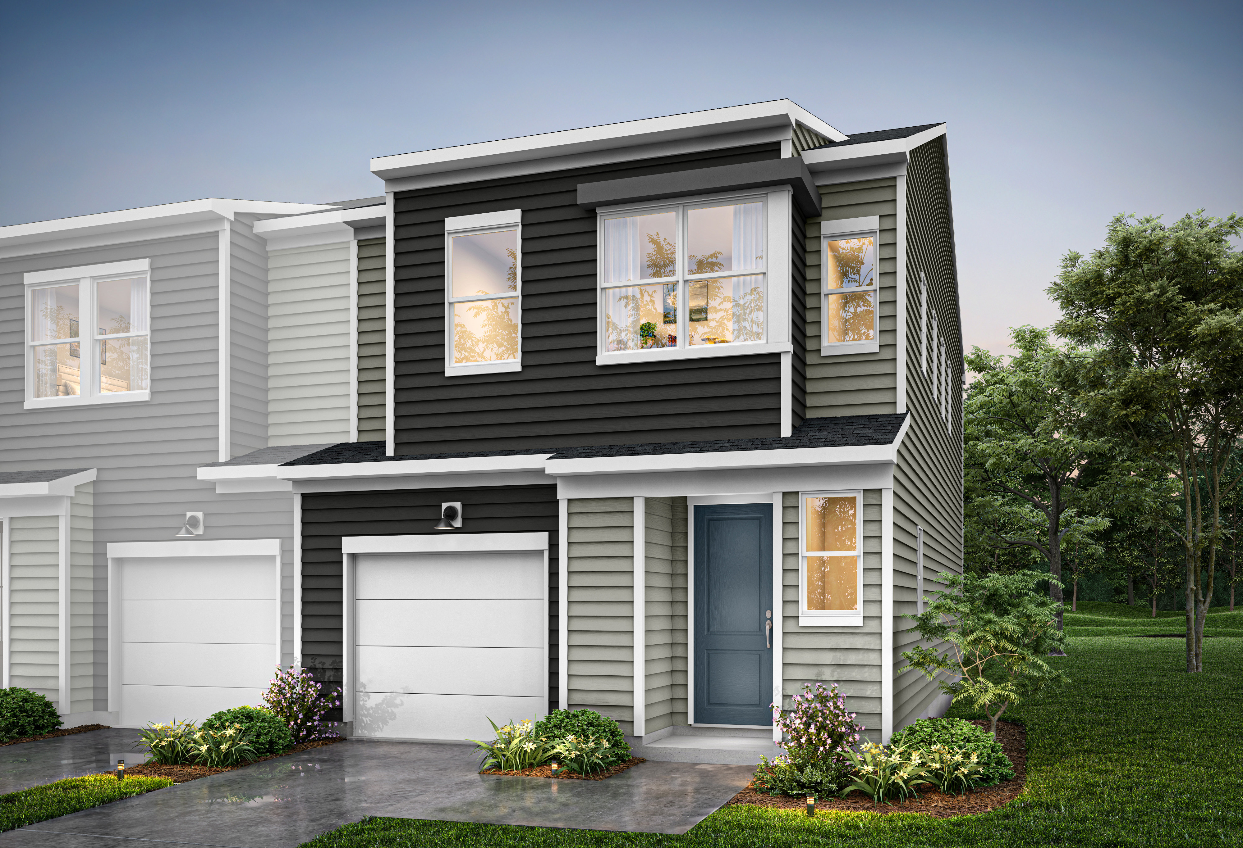 A modern two-story townhouse with a gray and black exterior, surrounded by lush greenery and a paved driveway leading to a garage.