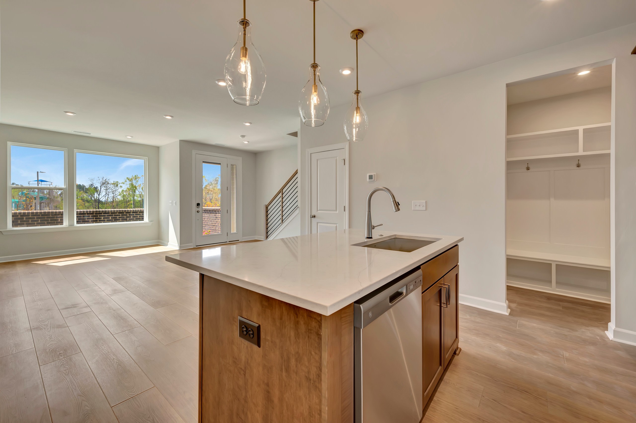 A modern, open-concept kitchen with a central island, pendant lighting, and a view of an adjacent room with built-in shelving.