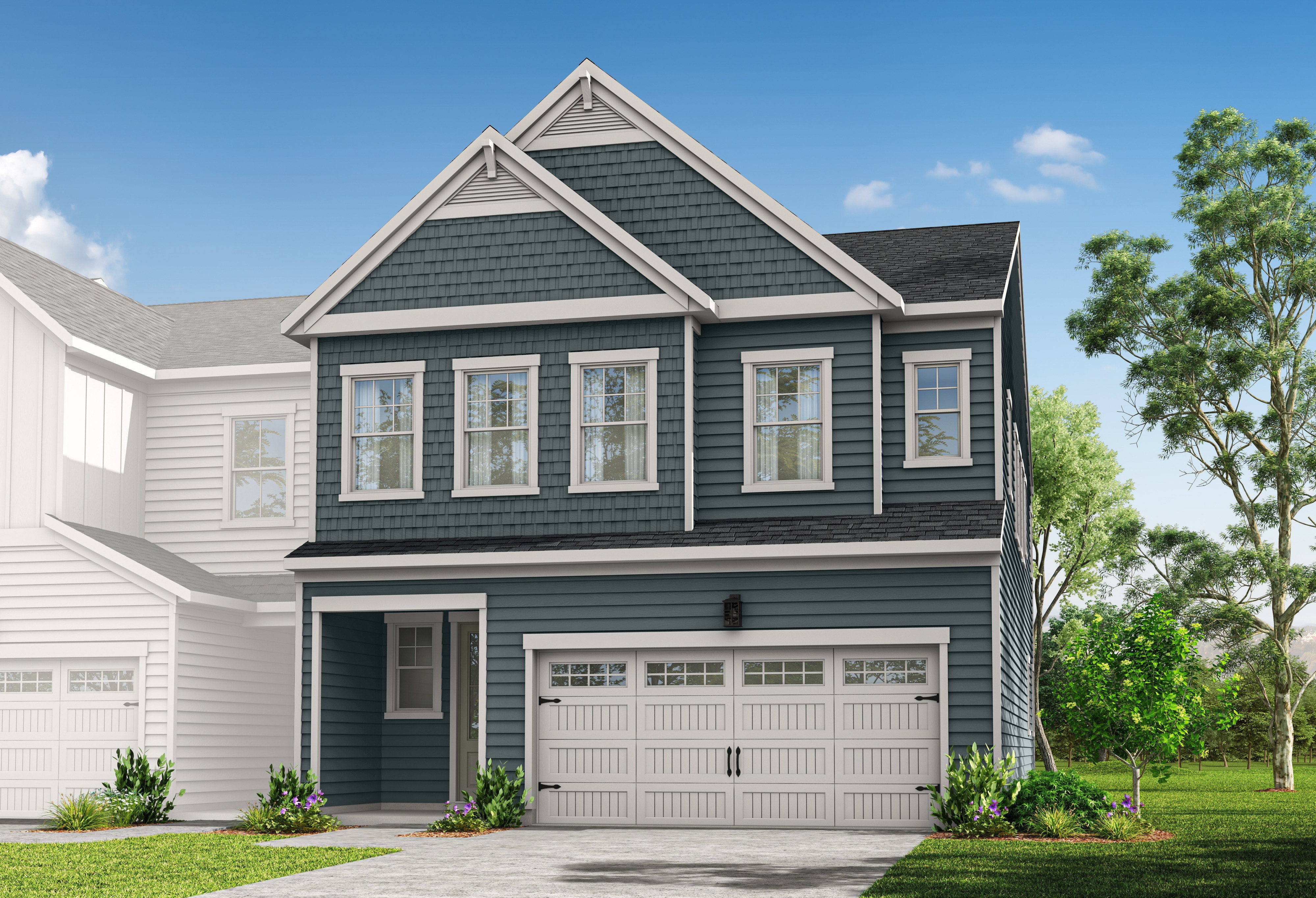 A two-story house with a gabled roof, white siding, and a garage door stands in a grassy yard surrounded by trees.