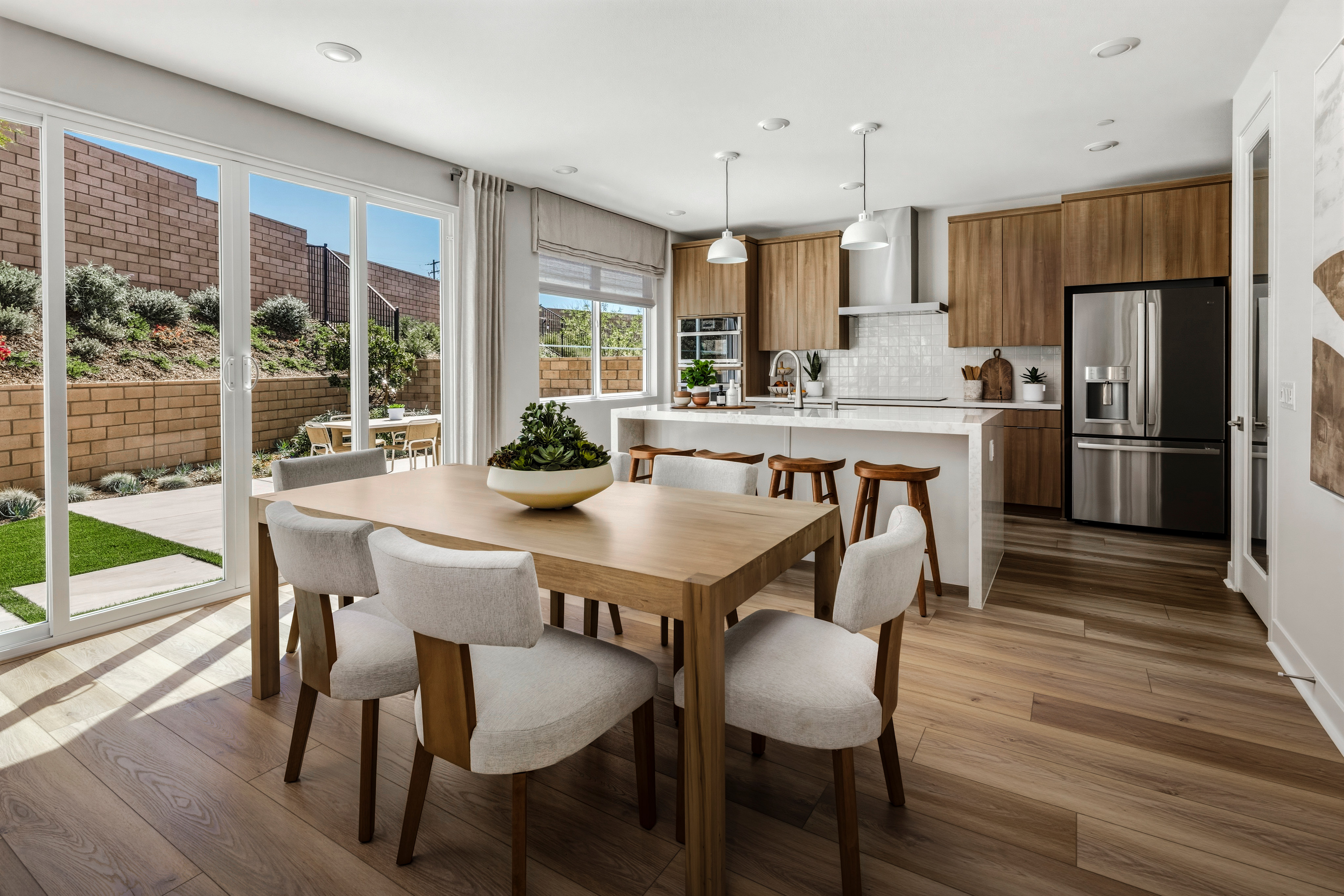 A modern and spacious kitchen and dining area with large windows overlooking a well-landscaped outdoor space.