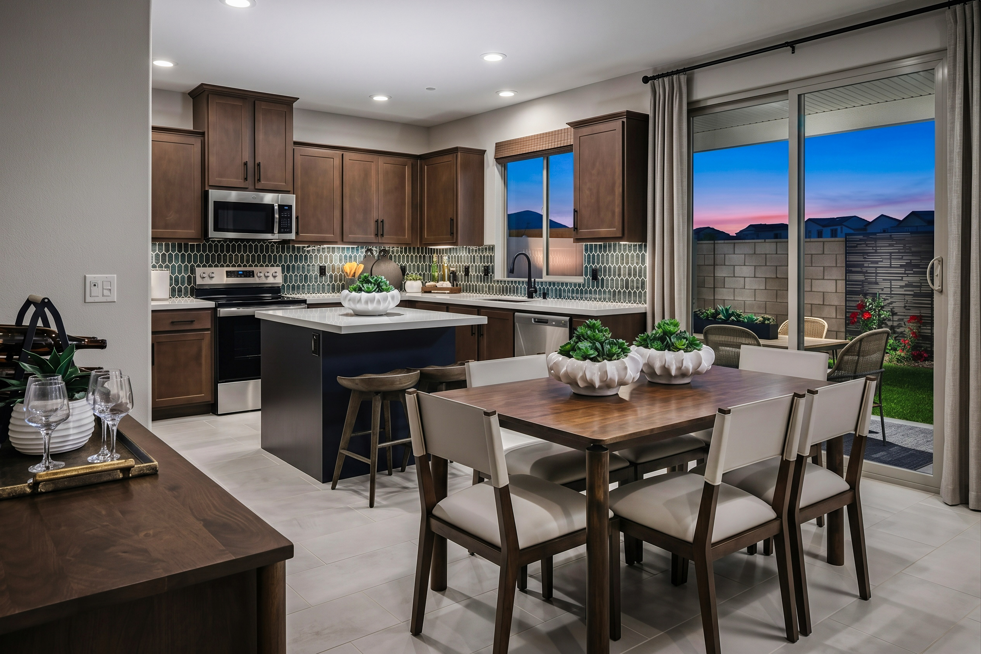 A modern kitchen and dining area with a dark wood island and dining table are in the foreground, while a backyard with a patio and lawn is visible through a sliding glass door in the background.