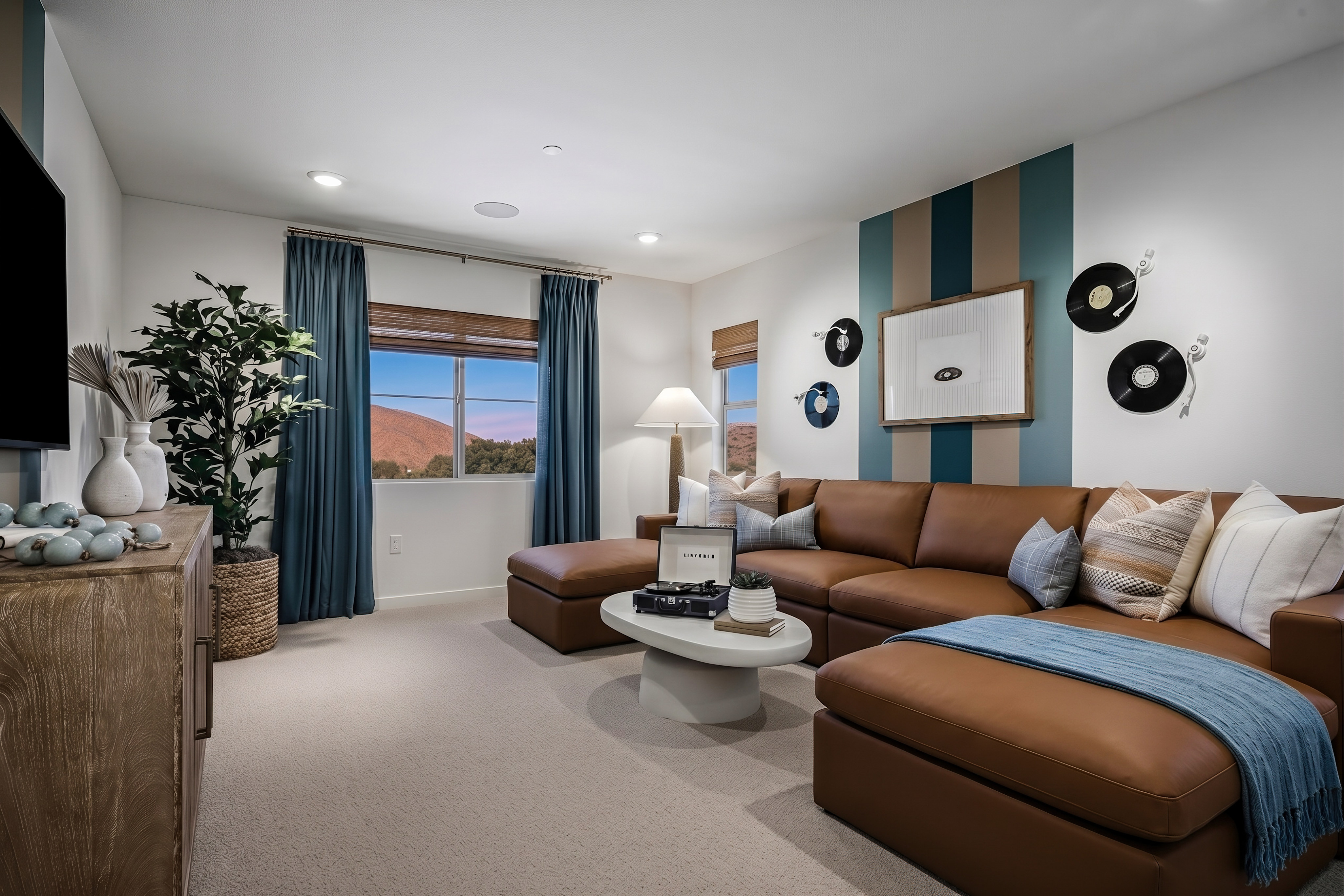 A plush brown sectional sofa with a blue throw blanket sits in the foreground, while the background features a wall with vertical stripes and decorative vinyl records.
