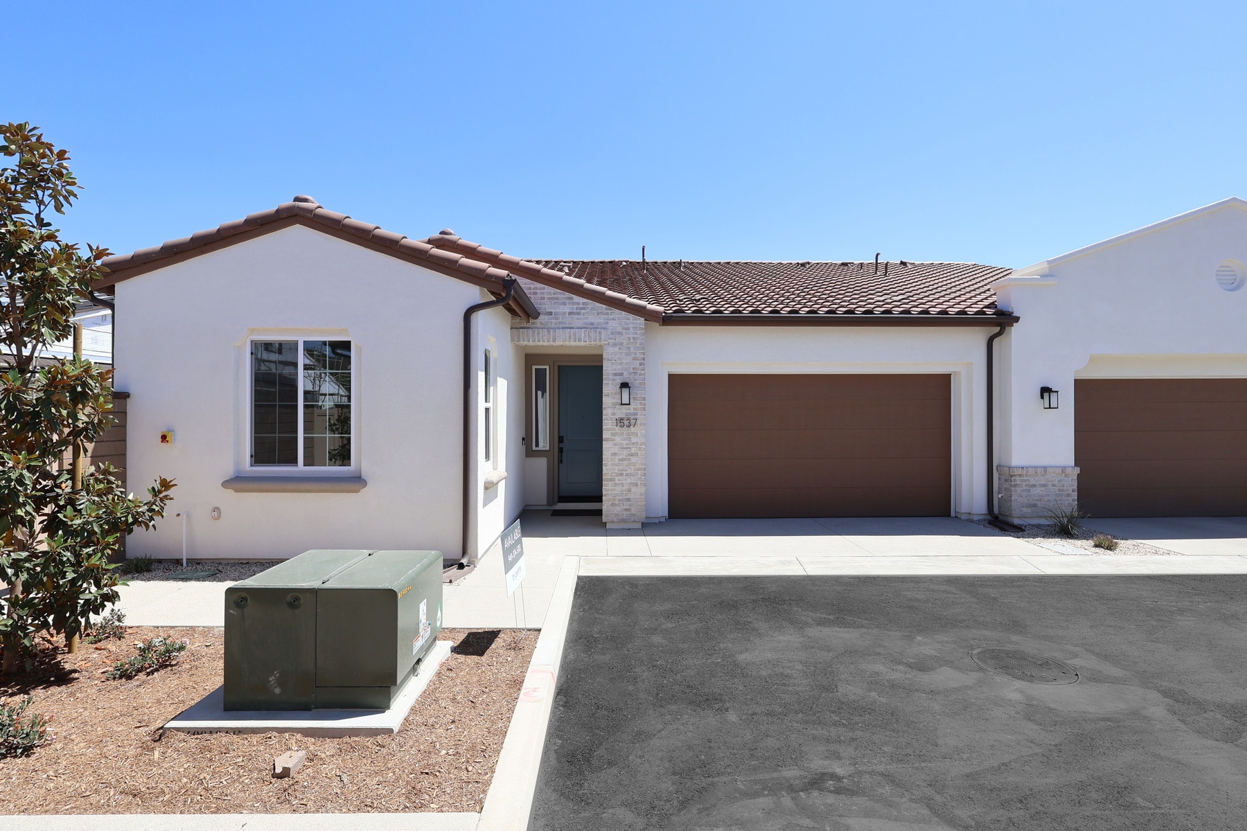A modern white house with a brown garage door sits in the foreground, while a clear blue sky stretches across the background.