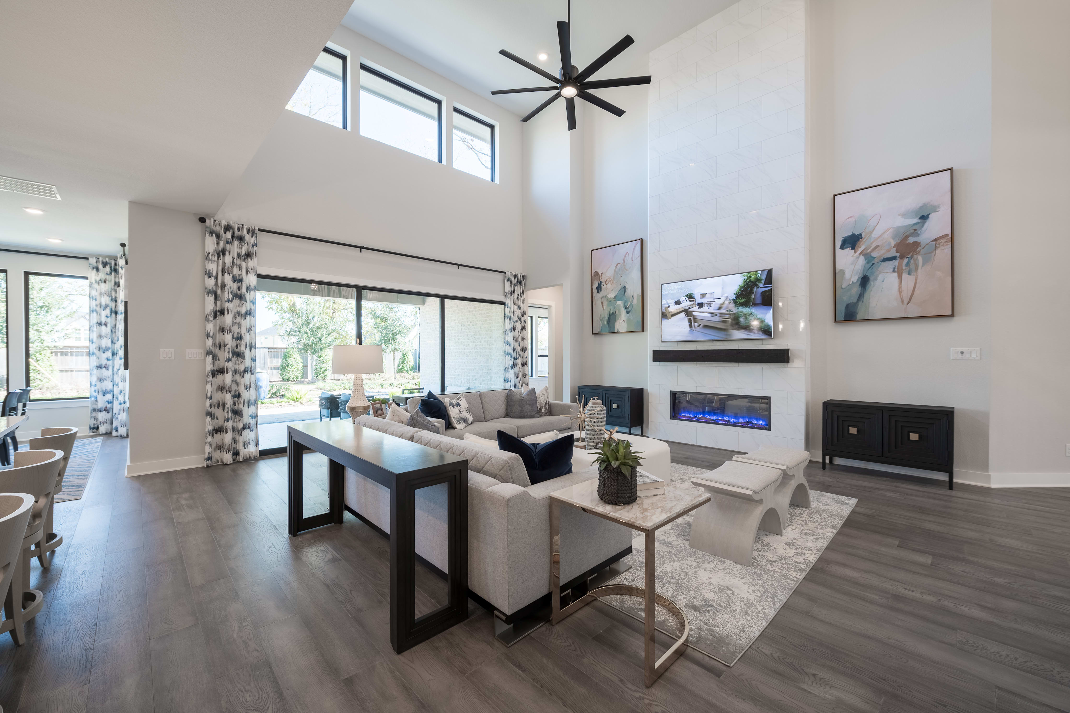 A spacious and modern living room with a large window, a fireplace, and various furniture pieces arranged in a cohesive layout.