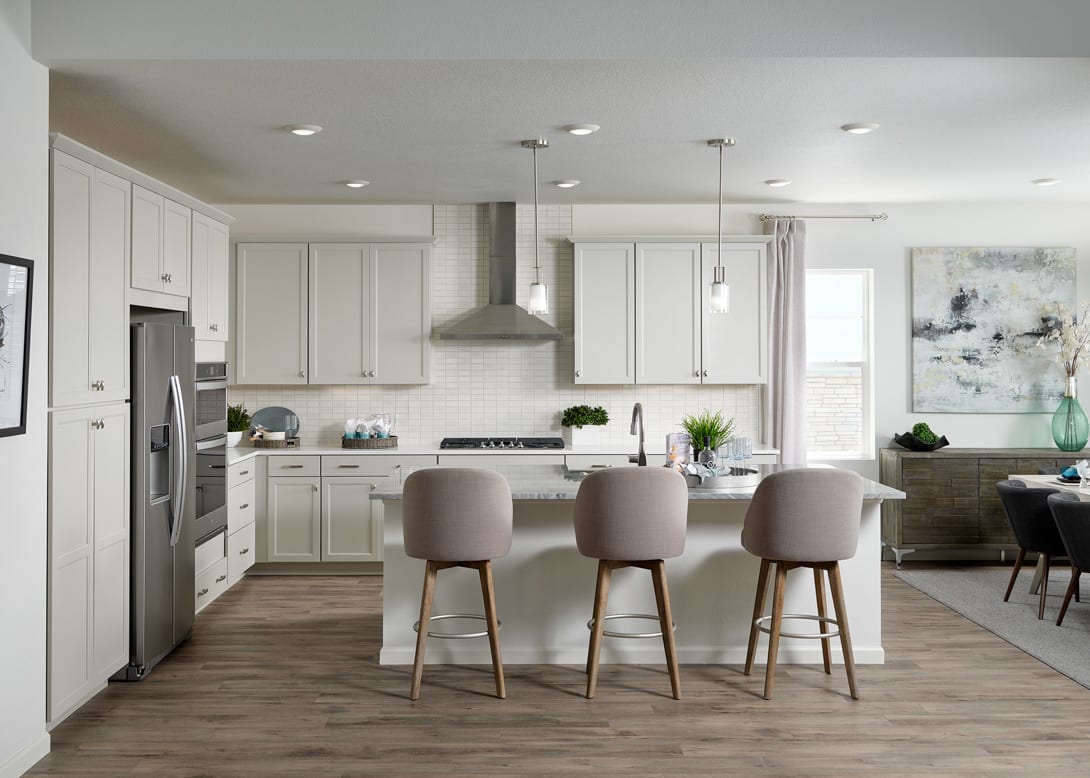 A modern, open-concept kitchen with white cabinets, a large island with bar stools, and a mix of natural and industrial elements throughout the space.
