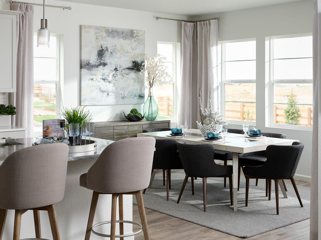 A modern and minimalist dining room with a large wooden table surrounded by comfortable upholstered chairs, a large abstract artwork on the wall, and a view of the outdoors through the large windows.