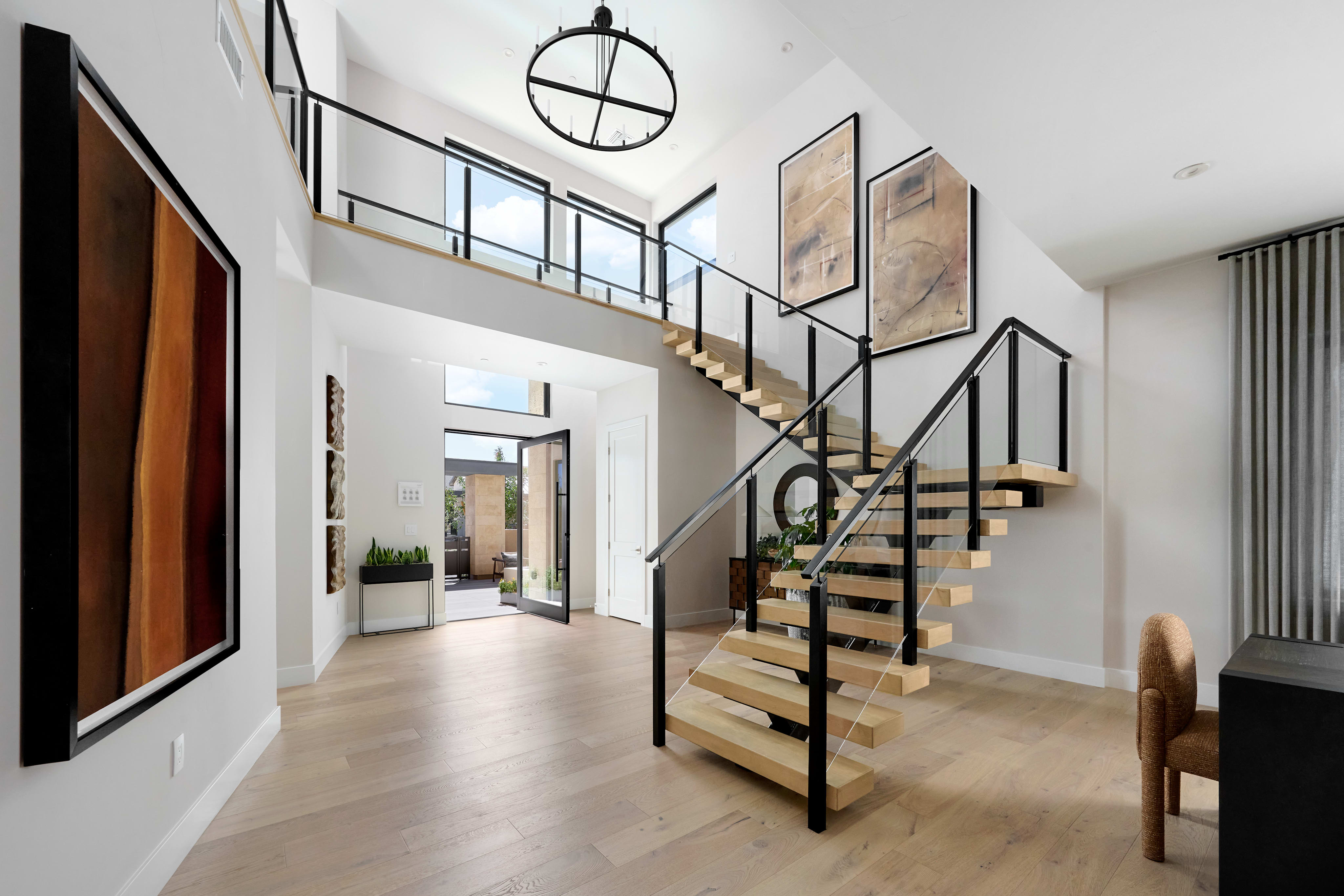 A modern and minimalist entryway with a striking spiral staircase, large windows, and a mix of natural and industrial design elements.