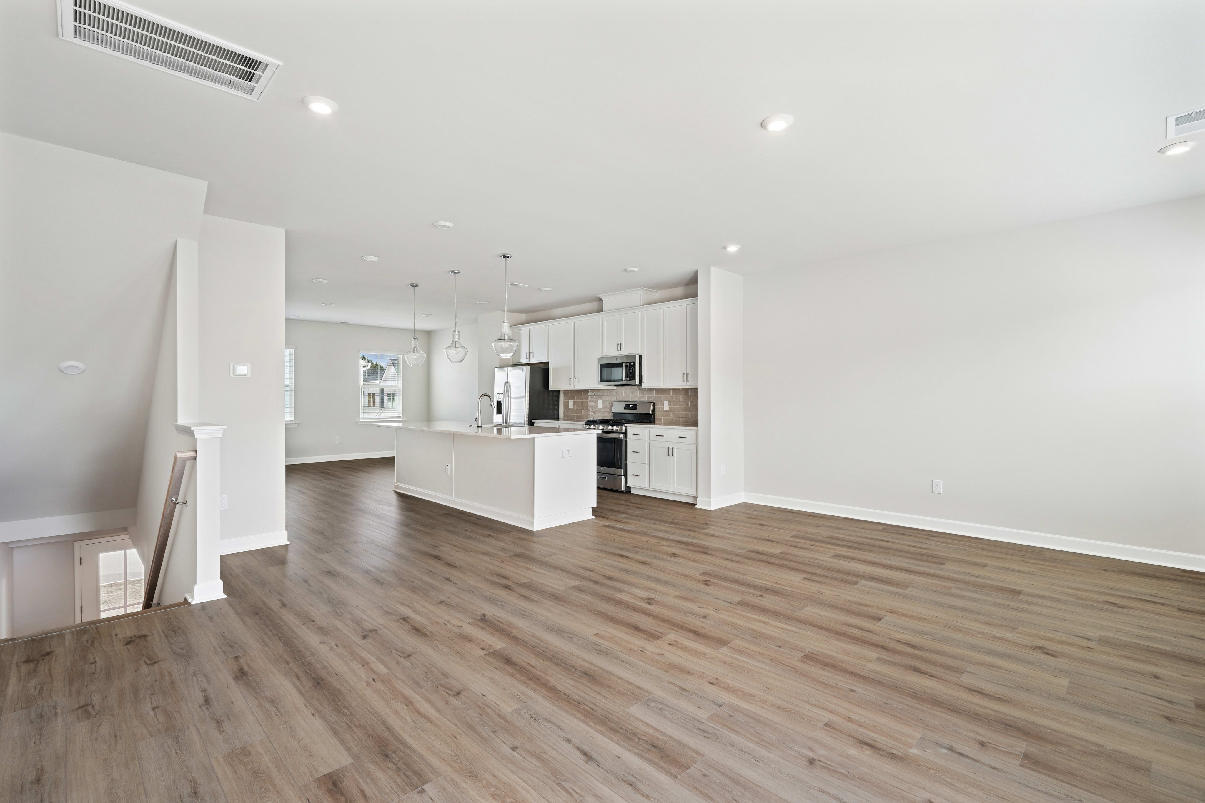 A spacious, open-concept living area with a modern kitchen and hardwood flooring, creating a bright and airy atmosphere.