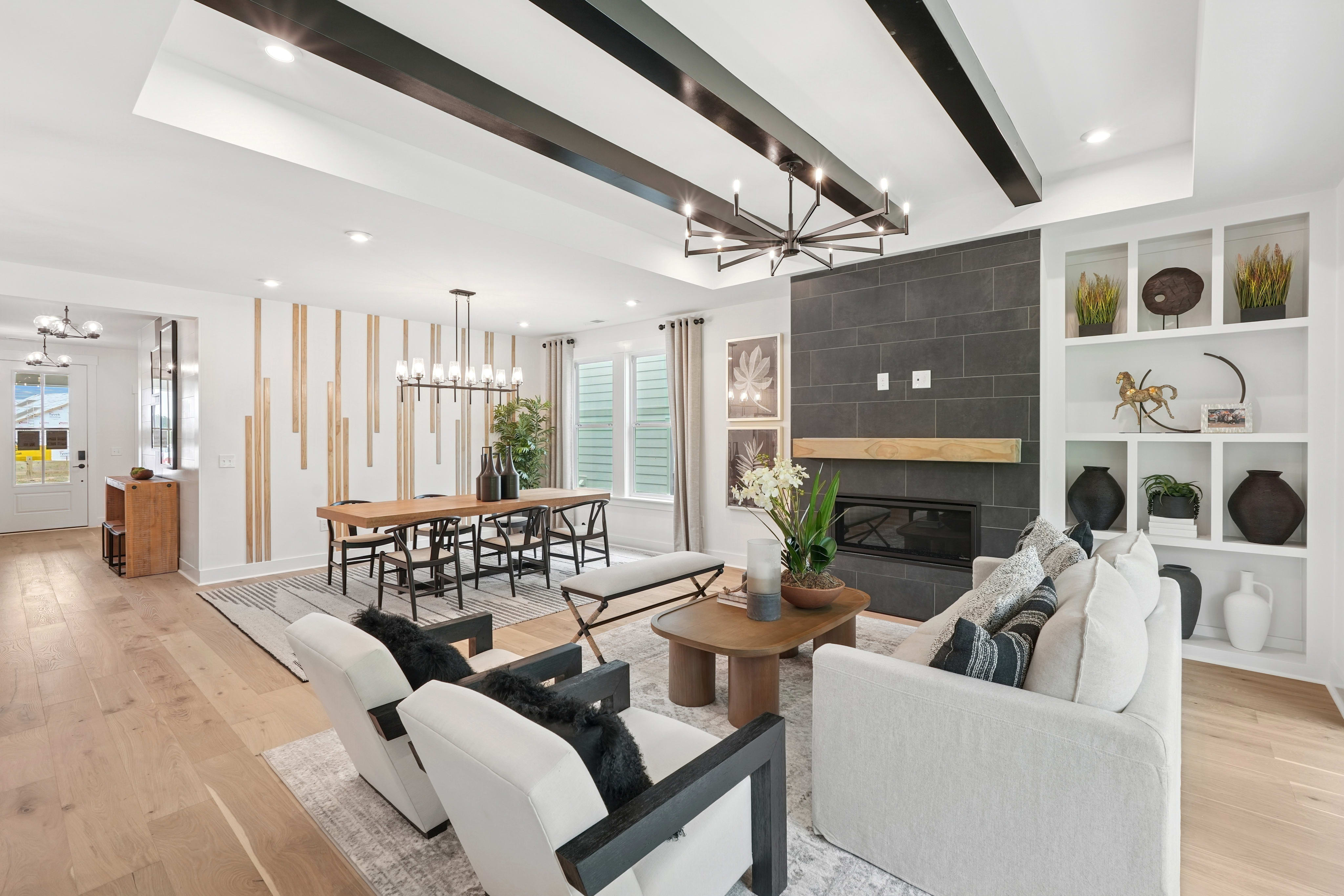 A modern and stylish living room with a fireplace, wooden beams on the ceiling, and a mix of contemporary and rustic furniture and decor elements.