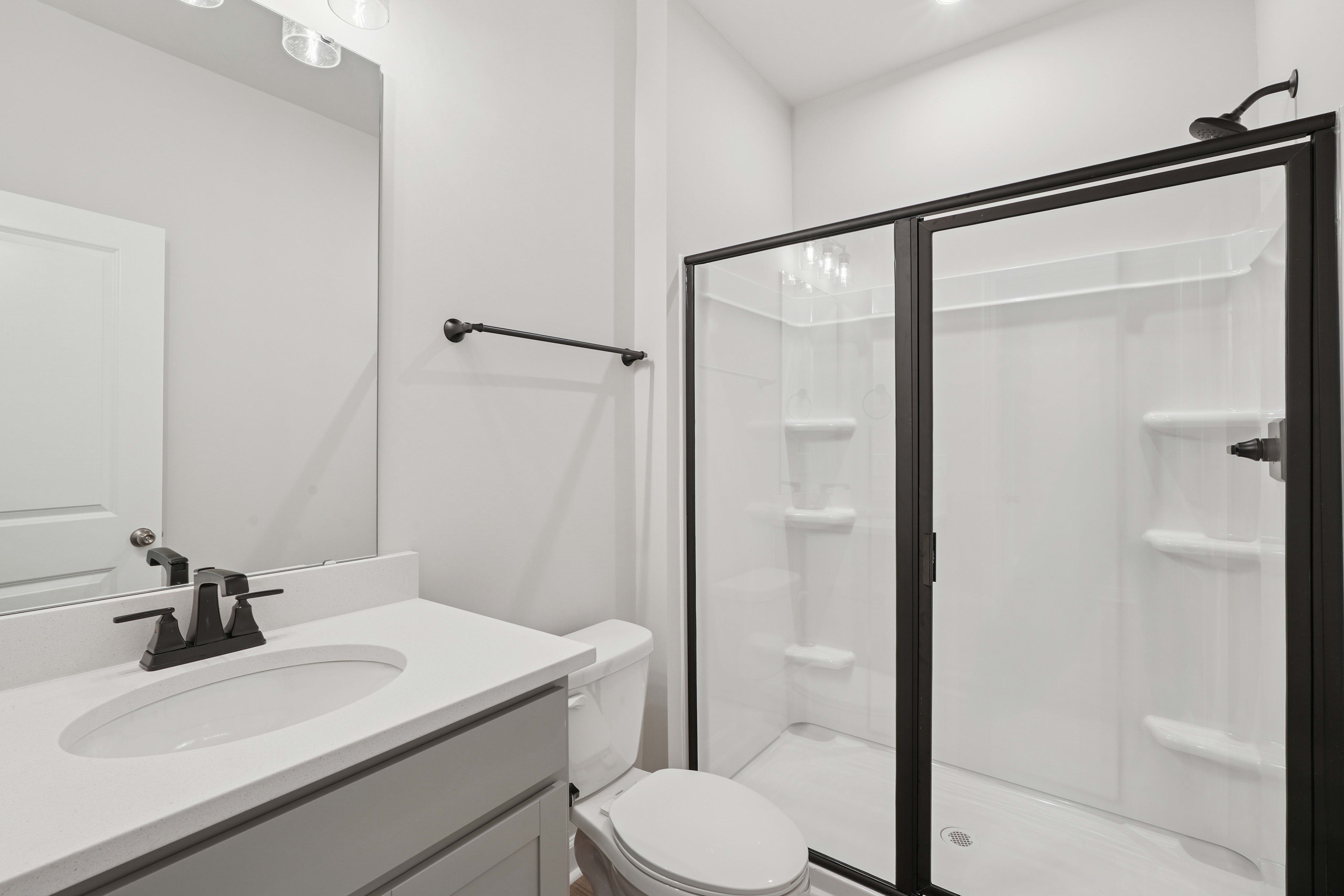 A modern, minimalist bathroom with a vanity, mirror, and shower enclosure in a clean, white and gray color scheme.