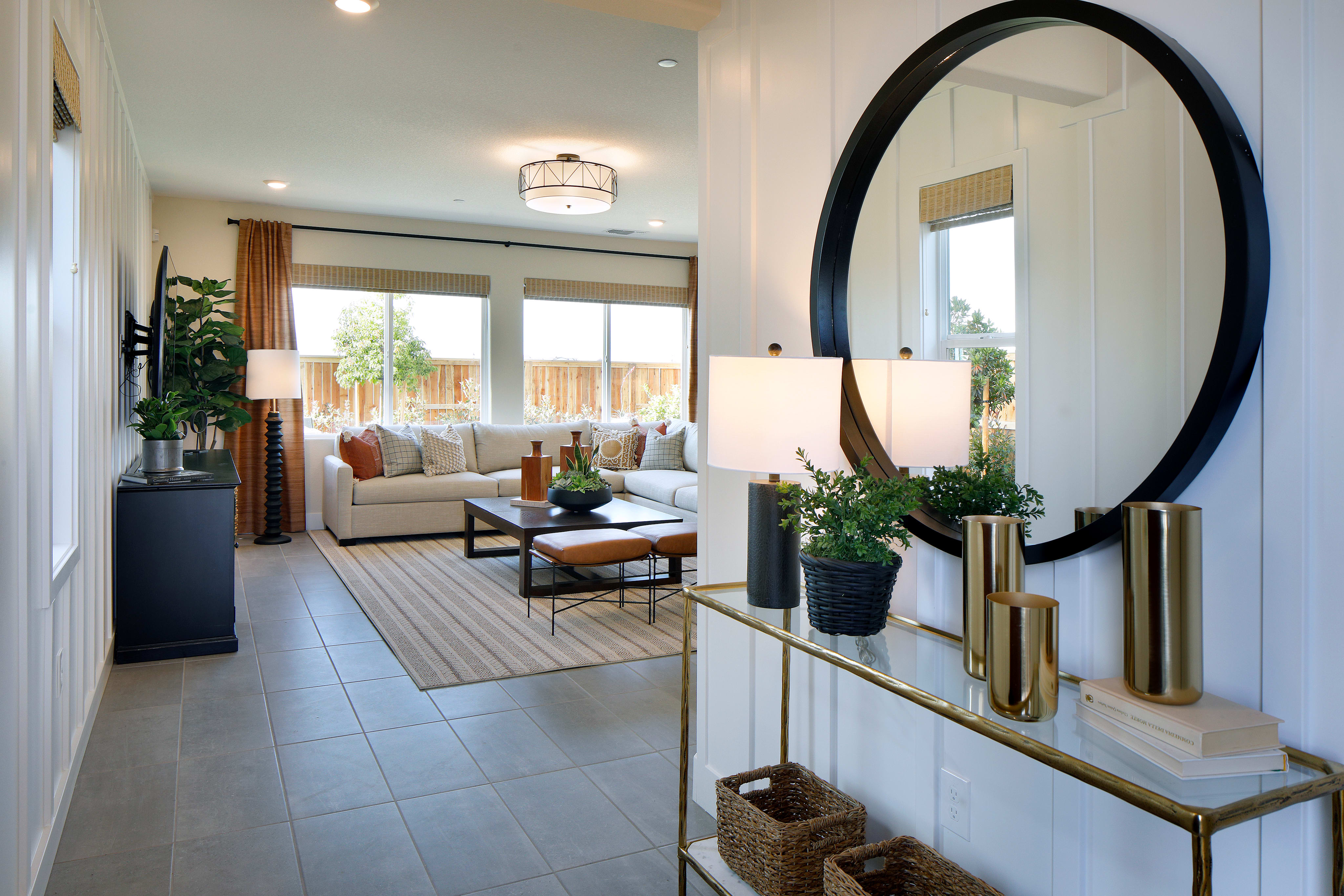 A spacious and well-designed living room with a large mirror, decorative accents, and a cozy seating area visible through an open doorway.