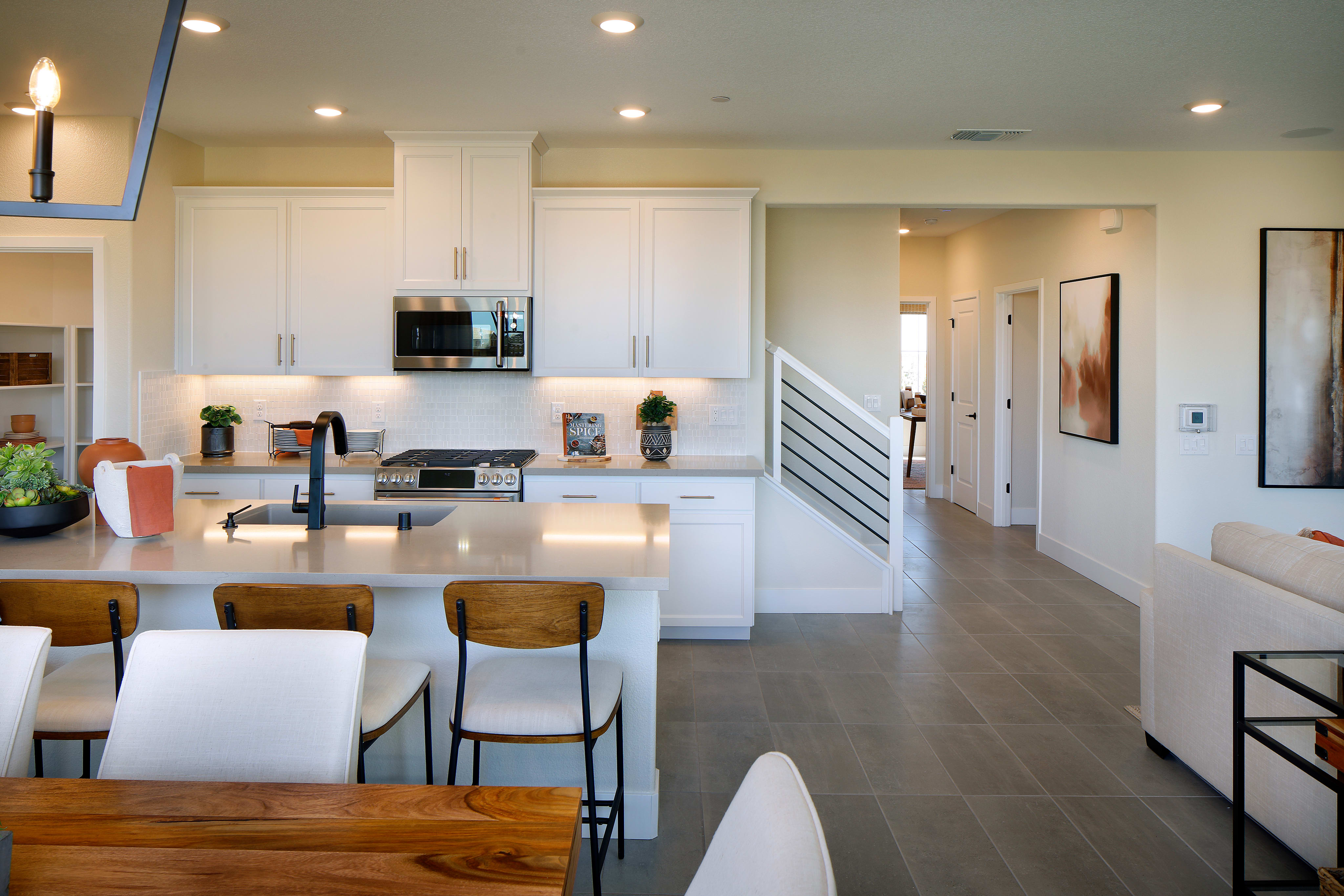A modern, open-concept kitchen and dining area with white cabinets, wooden accents, and a tiled floor.