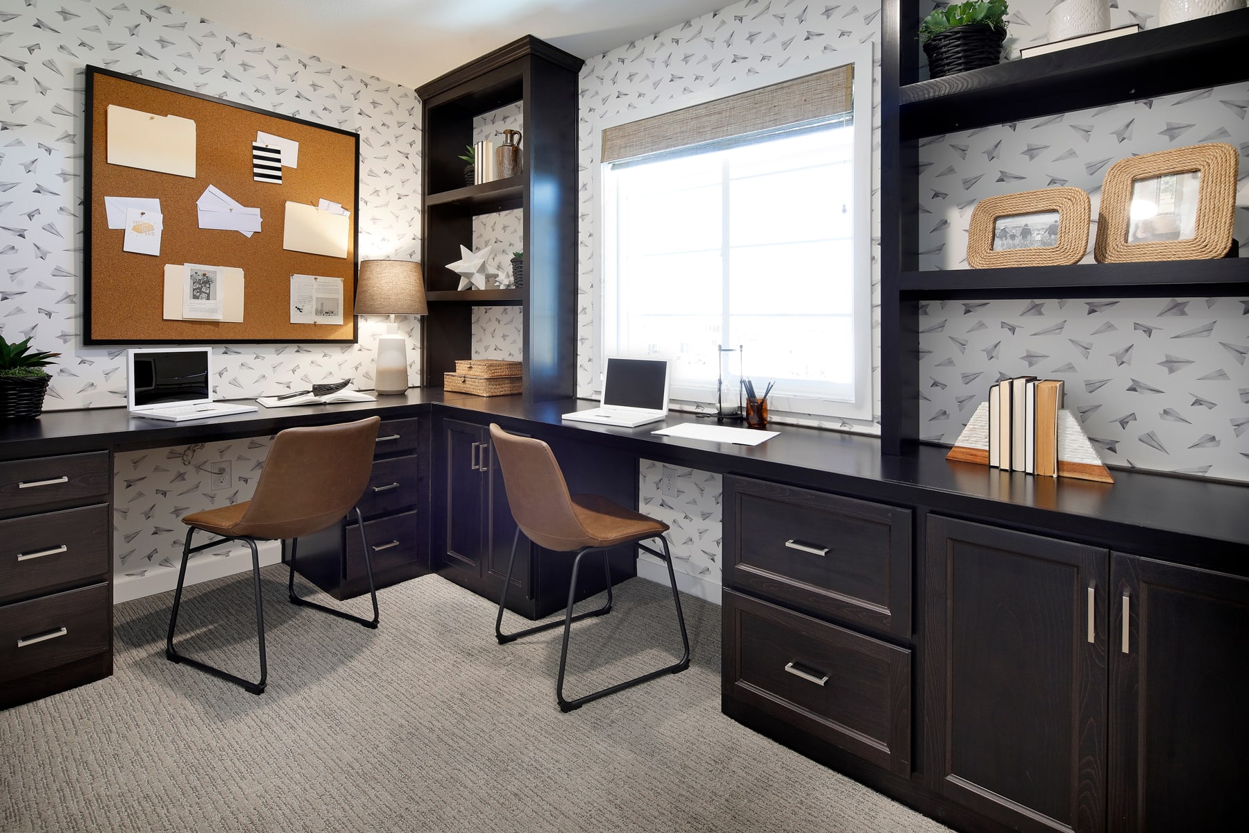 A modern and organized home office space with dark wooden furniture, shelves, and a large corkboard for notes and reminders.