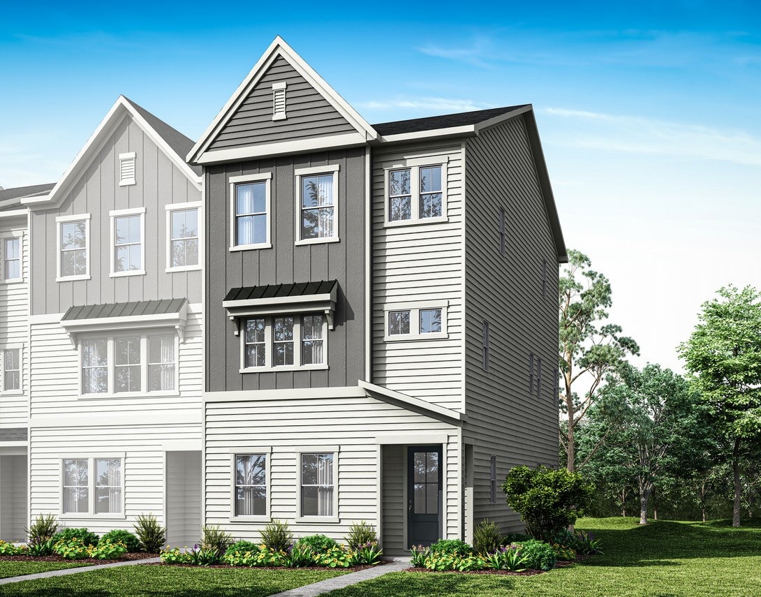 A modern, multi-story townhouse with gray siding and a peaked roof stands in a lush, green landscape with trees in the background.