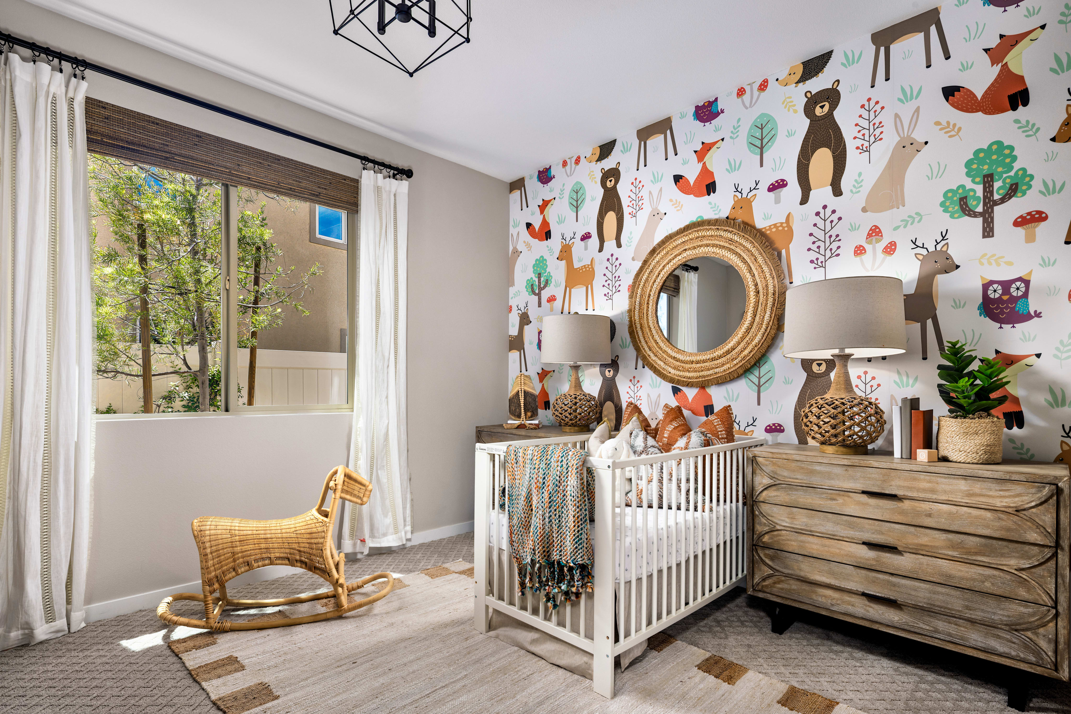 A cozy and whimsical nursery with a white crib, wooden dresser, and a rocking chair, surrounded by a vibrant wall mural featuring various woodland creatures and nature elements.