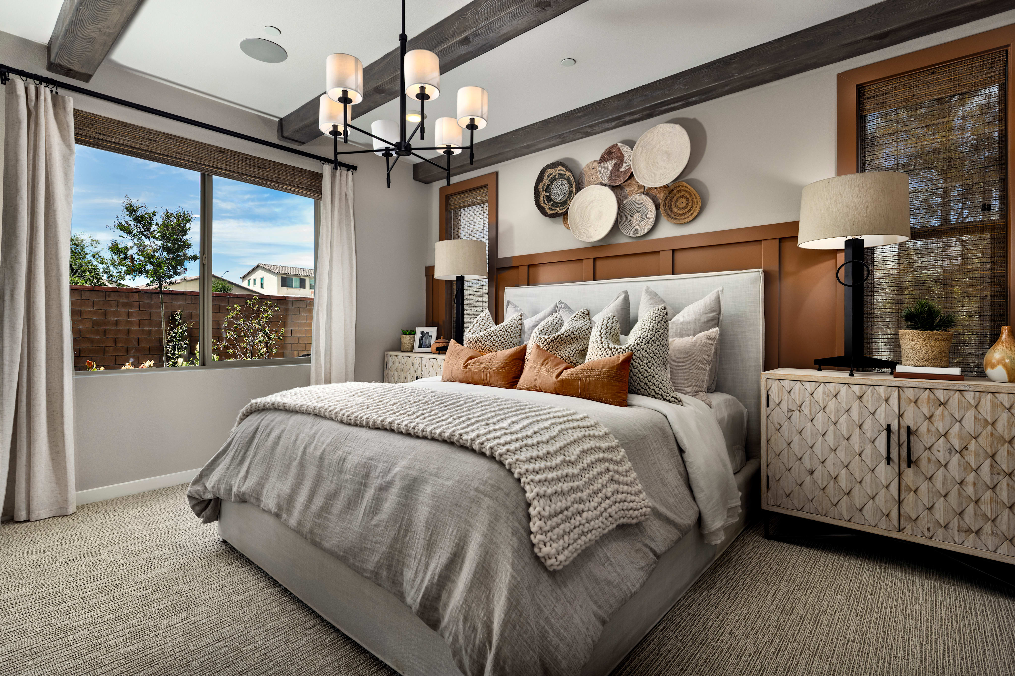 A cozy and inviting bedroom with a plush bed, wooden accents, and a large window overlooking a scenic outdoor landscape.