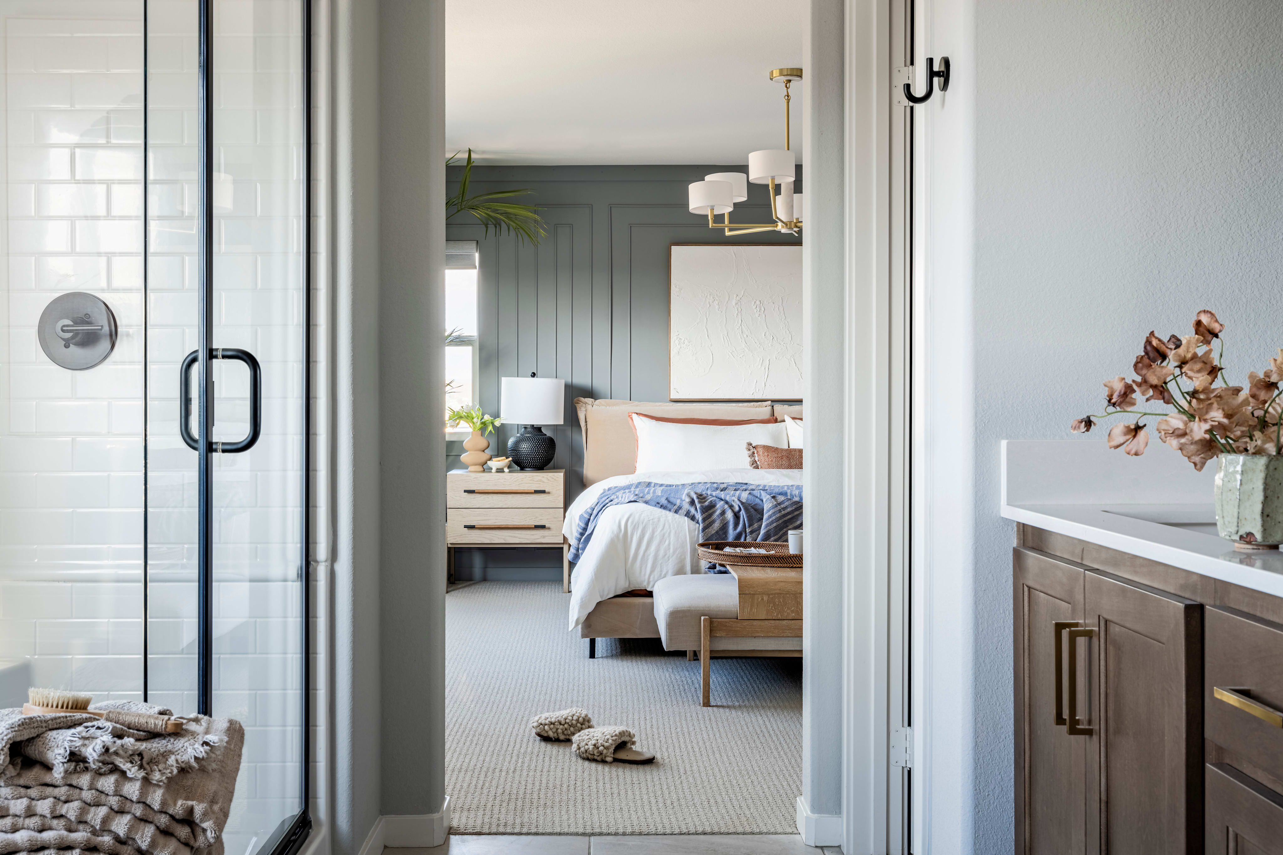 A cozy and inviting bedroom with a glass-enclosed shower, a wooden cabinet, and a plush rug in the foreground, leading to a warm and comfortable sleeping area in the background.