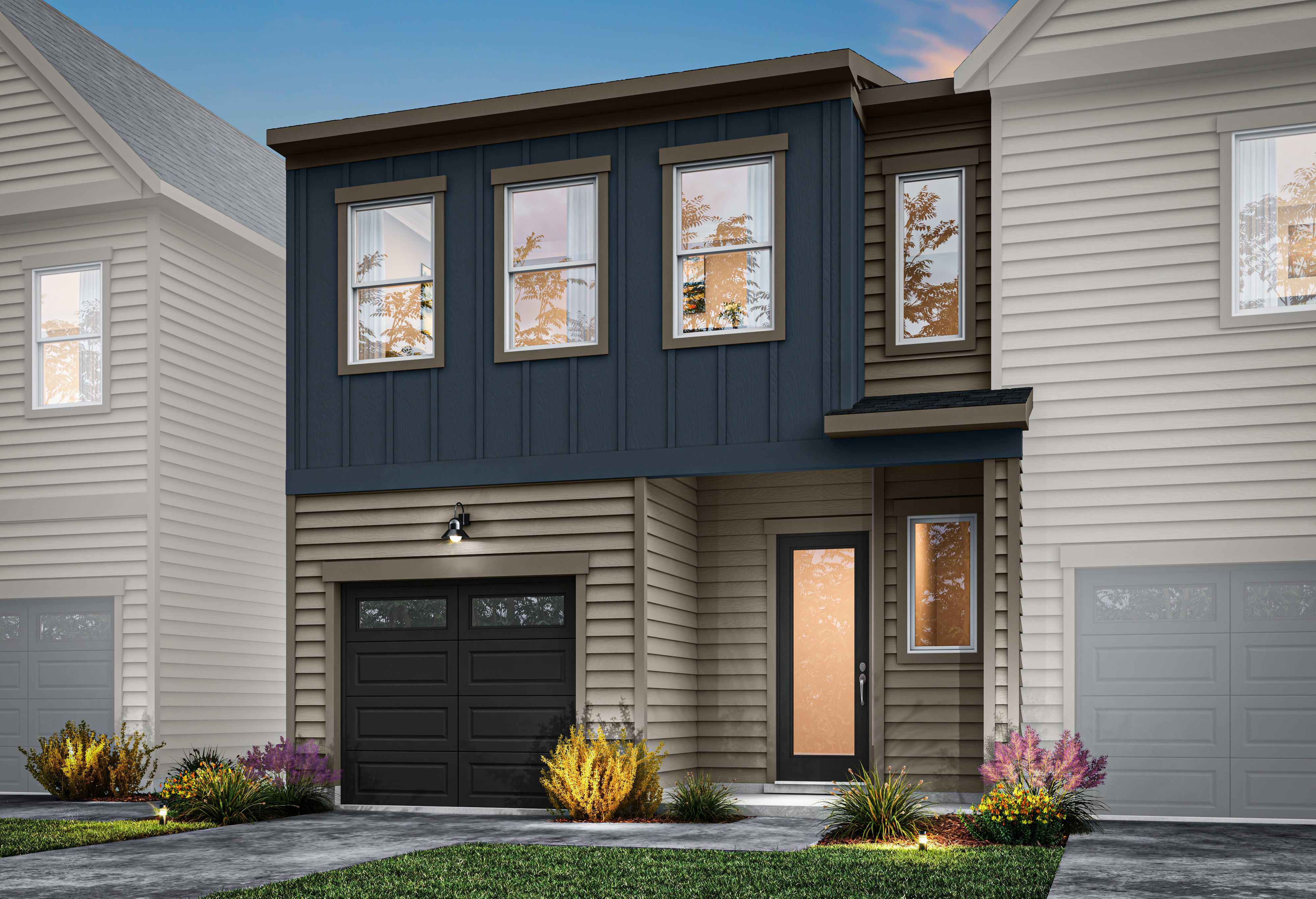 A modern two-story townhouse with a black garage door, large windows, and a colorful landscaped front yard.