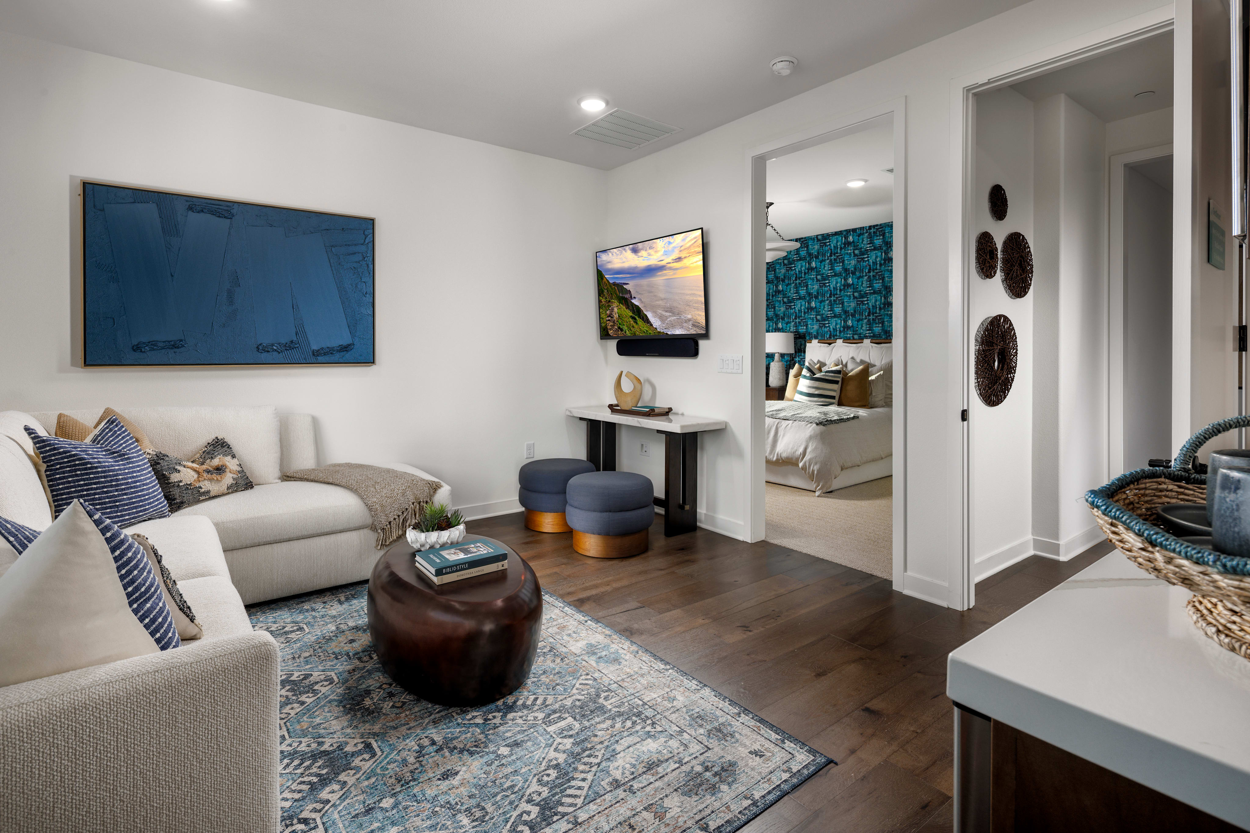 A cozy and well-decorated living room with a comfortable sofa, colorful artwork on the walls, and various decorative elements such as a side table, baskets, and a rug.