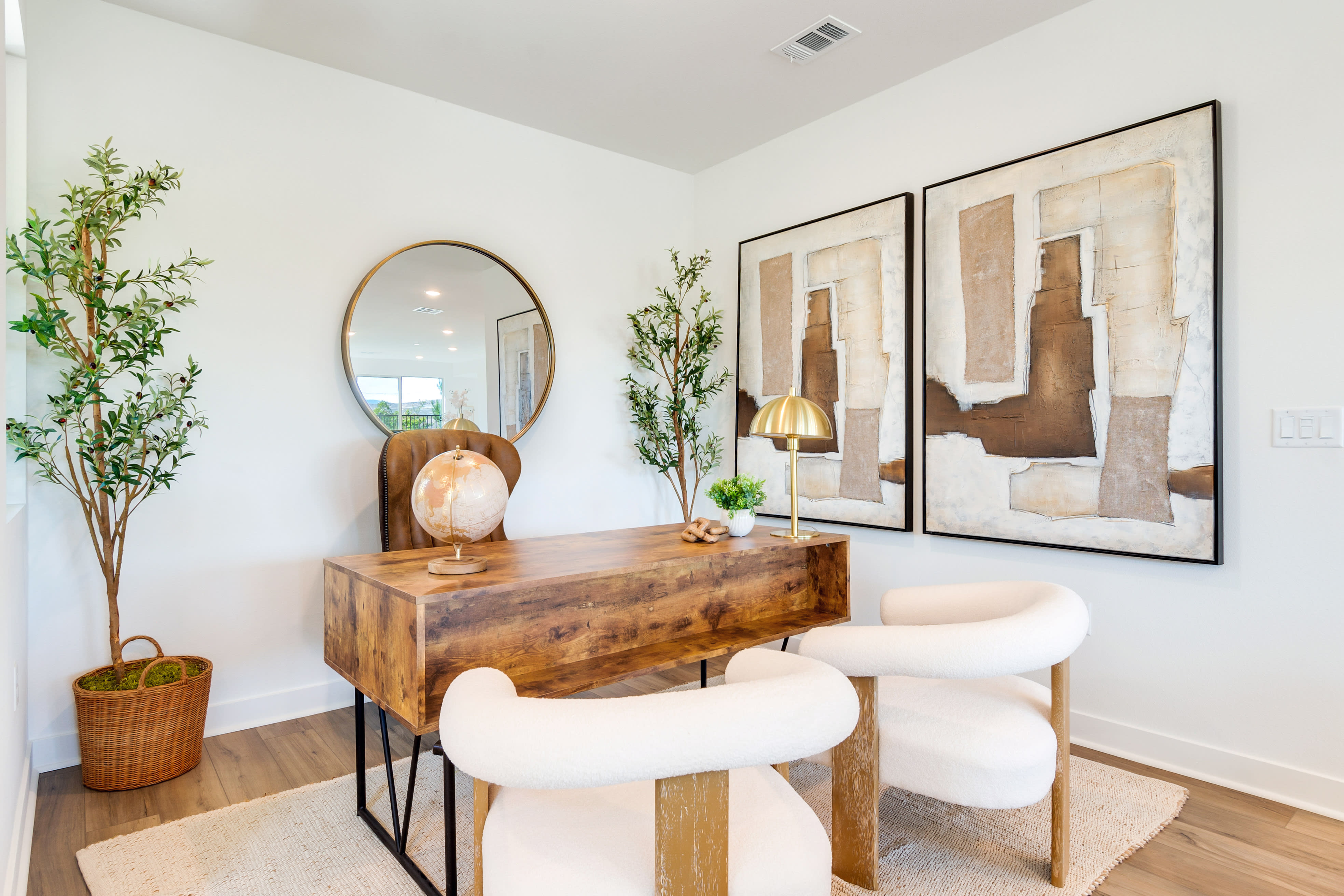 A cozy and inviting entryway with a rustic wooden console table, a large round mirror, and abstract artwork on the walls, complemented by potted plants and a woven basket.