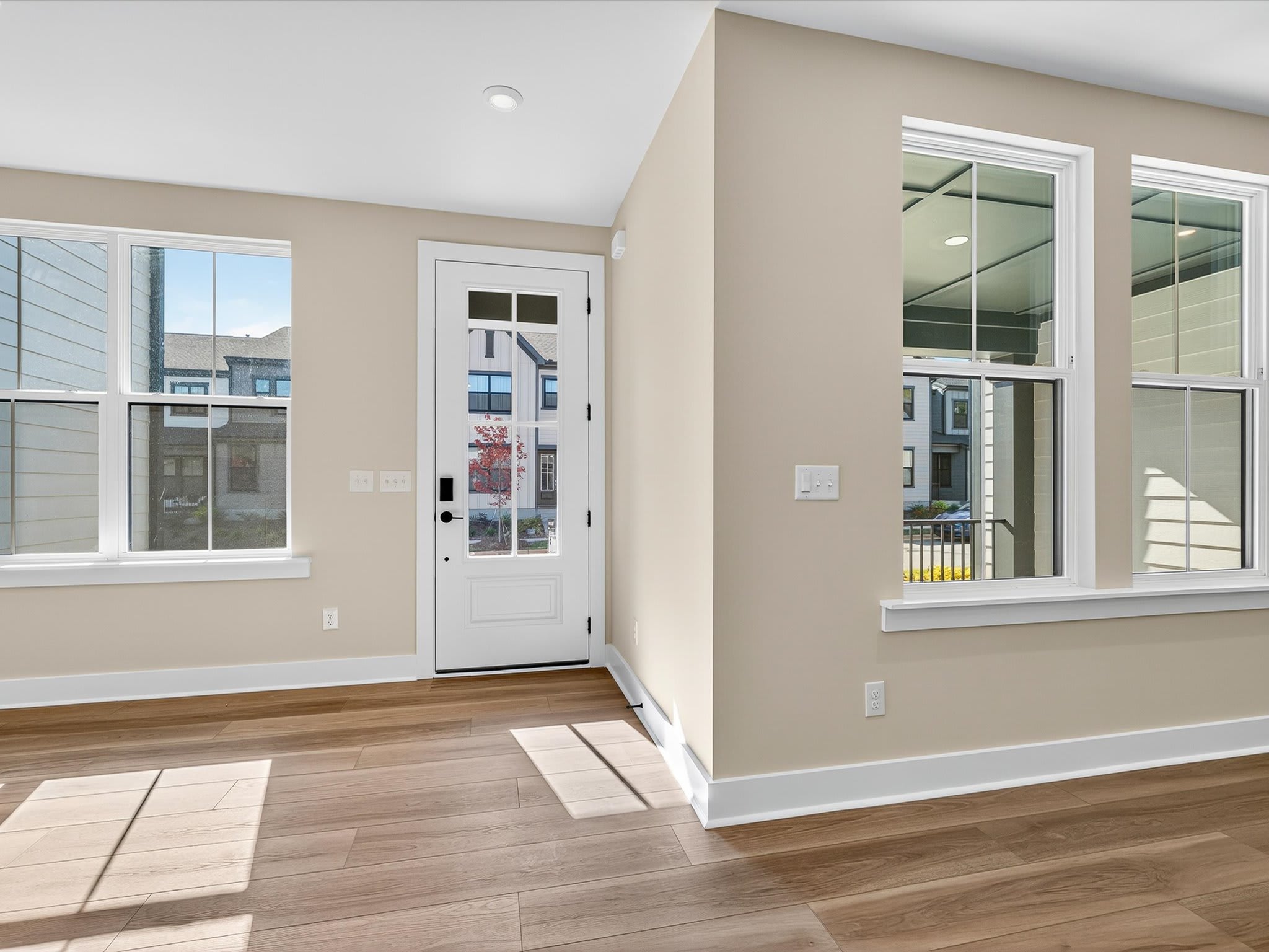 A spacious and well-lit interior with hardwood floors, neutral-colored walls, and large windows providing a view of the exterior.