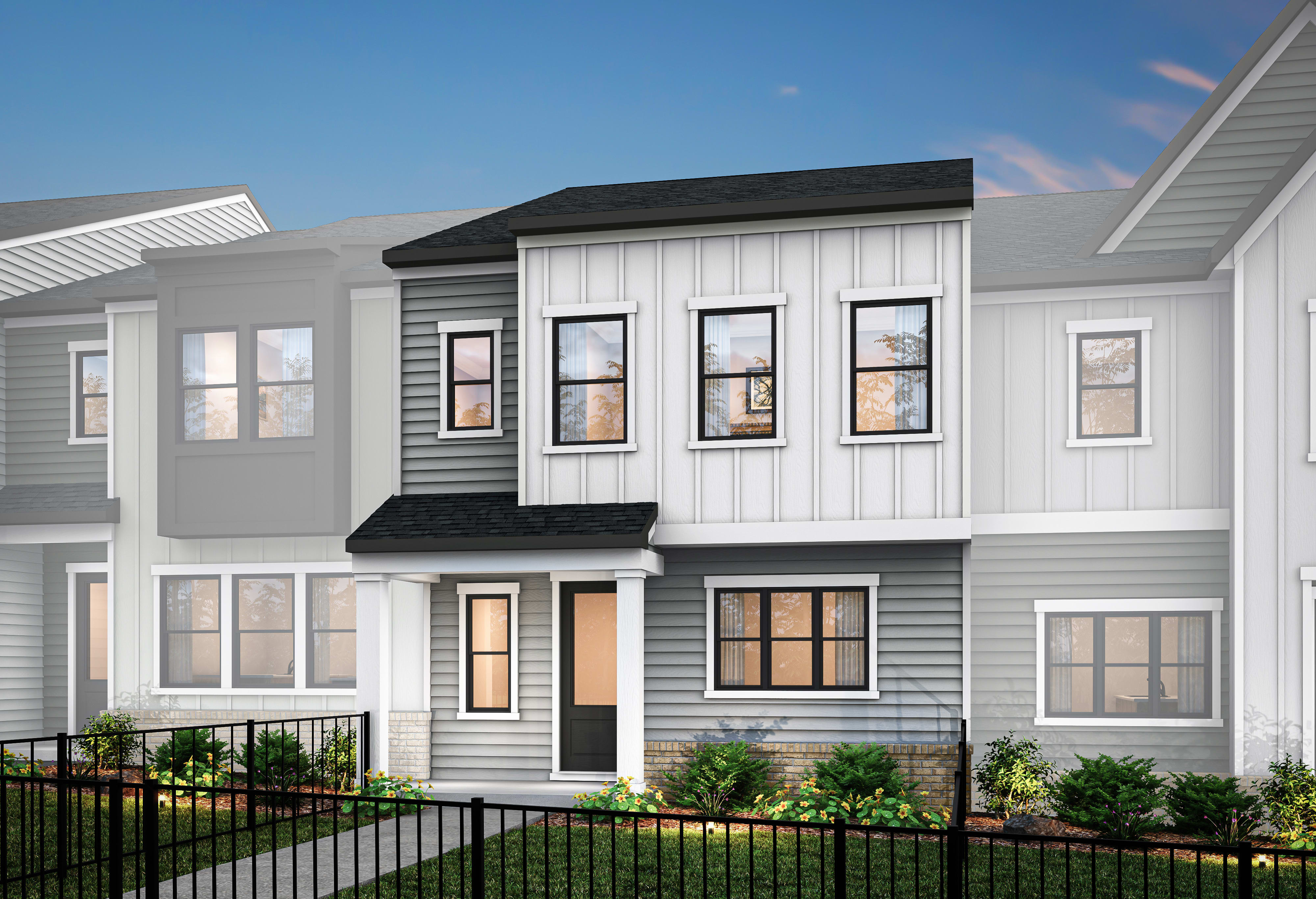 A modern, two-story townhouse with a gray exterior, white trim, and a black roof, surrounded by a metal fence and landscaping in the foreground.