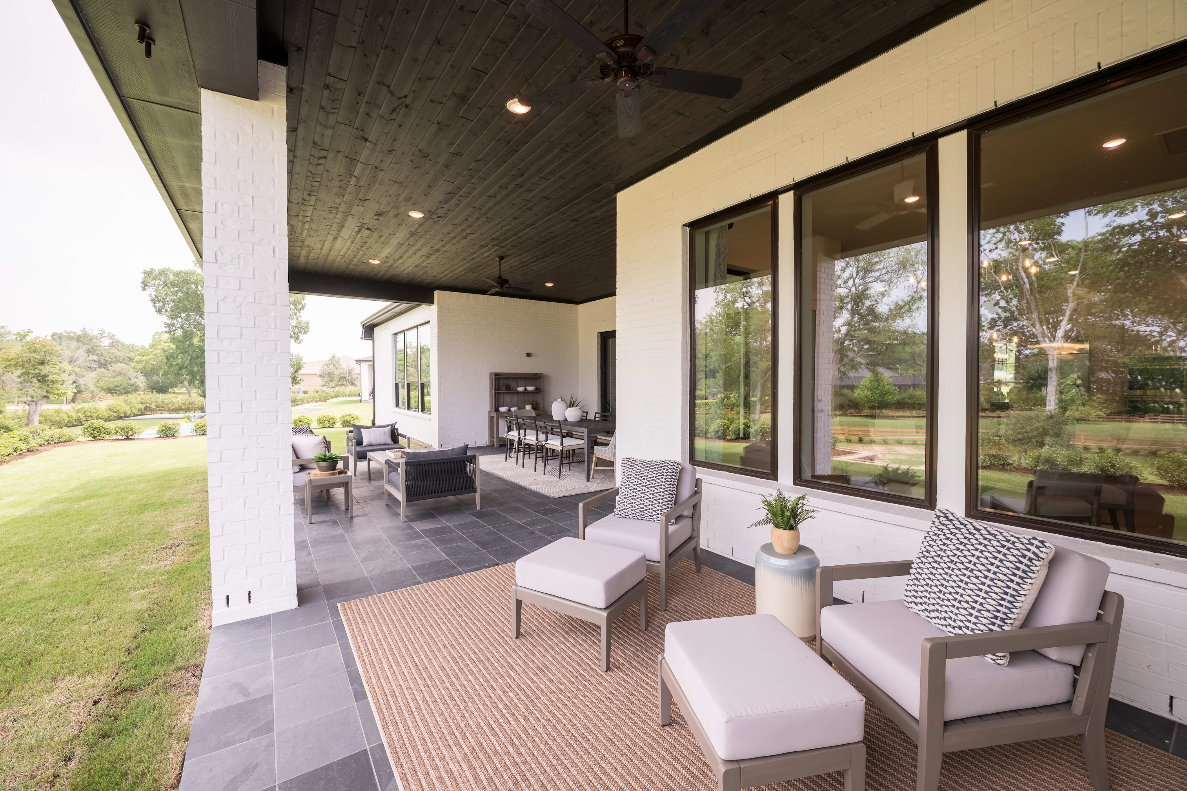 A spacious and modern patio with comfortable seating arrangements, surrounded by a lush, well-manicured lawn and trees, creating a serene and inviting outdoor living space.