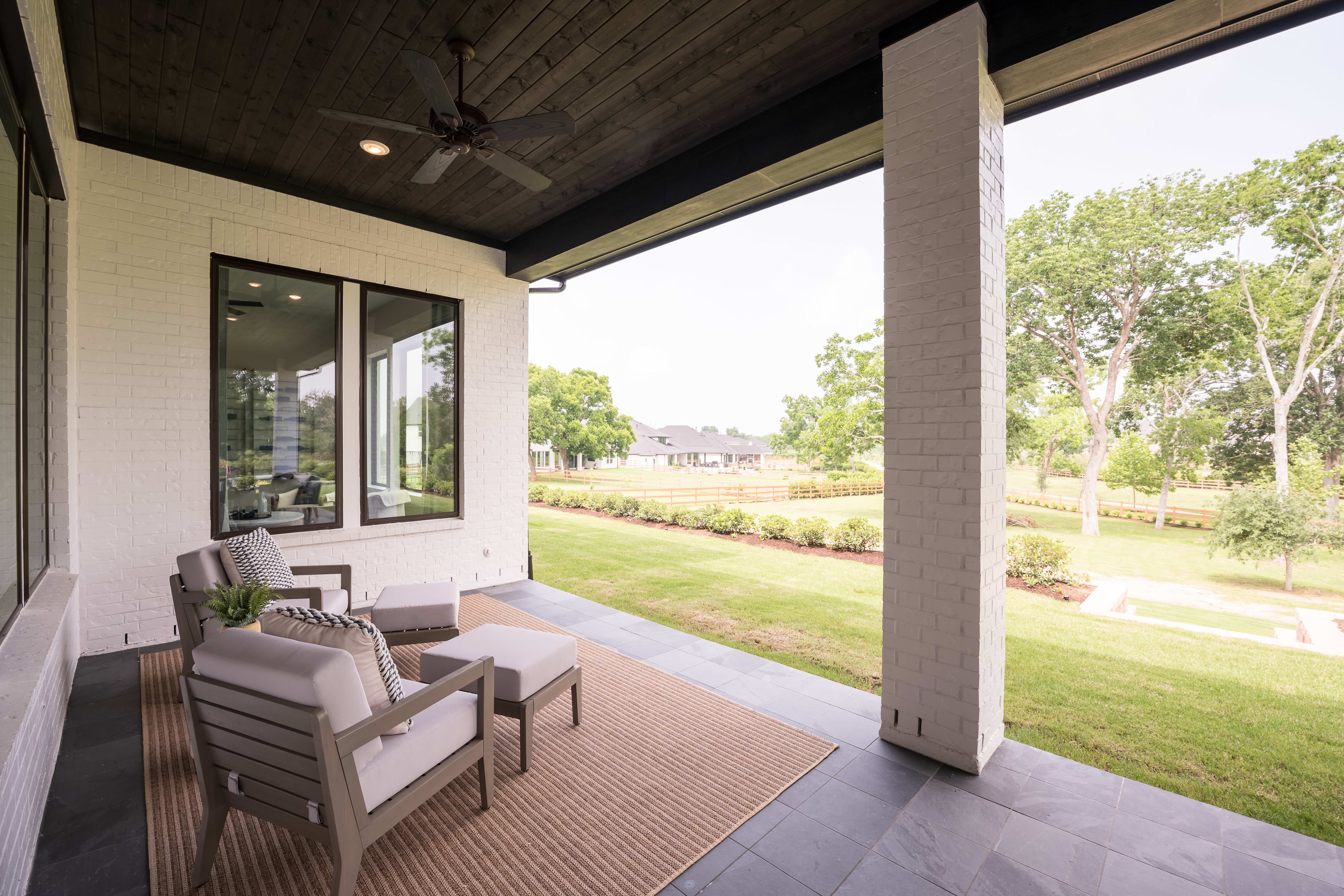 A cozy outdoor patio with comfortable seating overlooking a lush, green lawn and trees in the background.