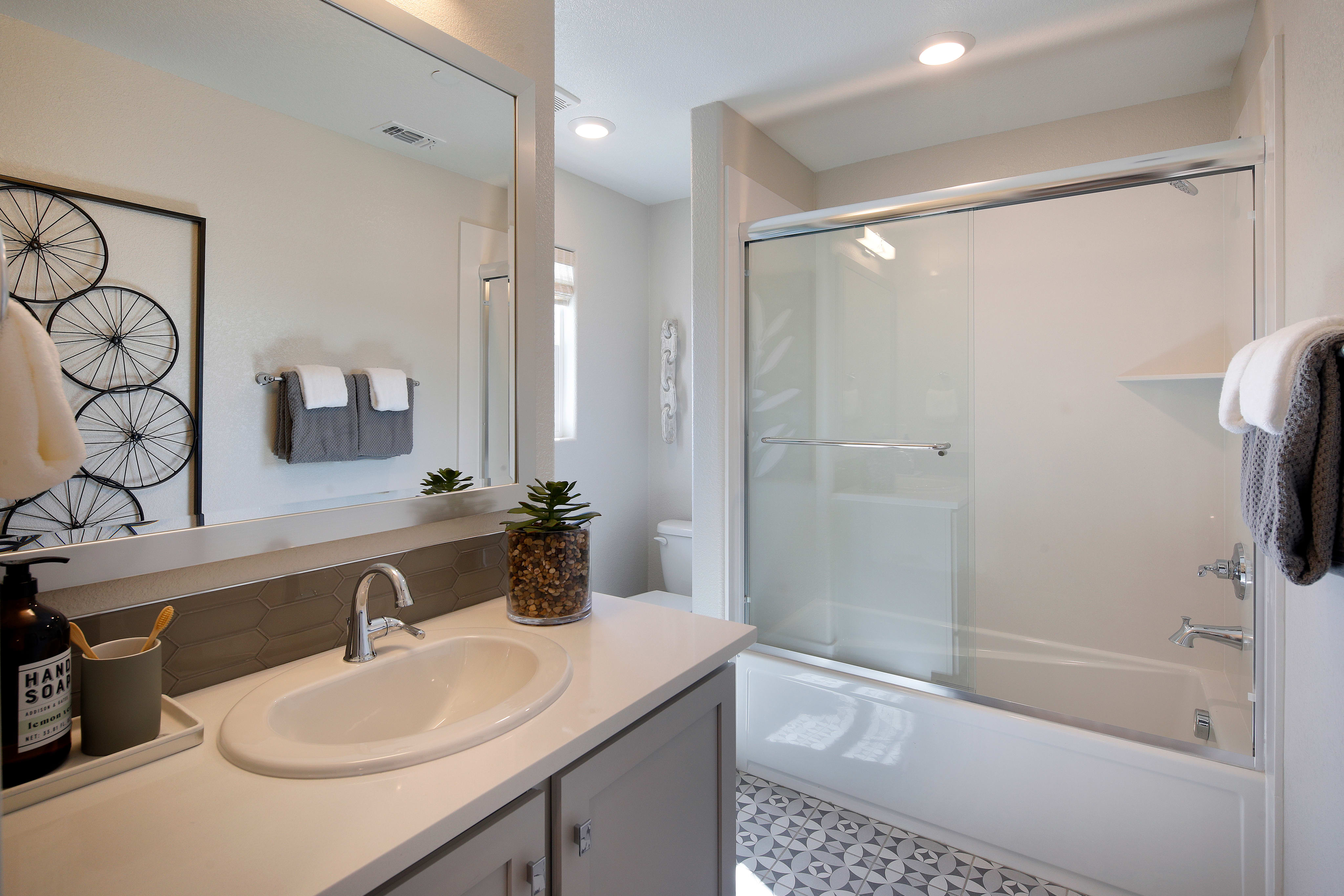 A modern bathroom with a vanity, sink, and a glass-enclosed shower area, featuring a minimalist and clean design aesthetic.