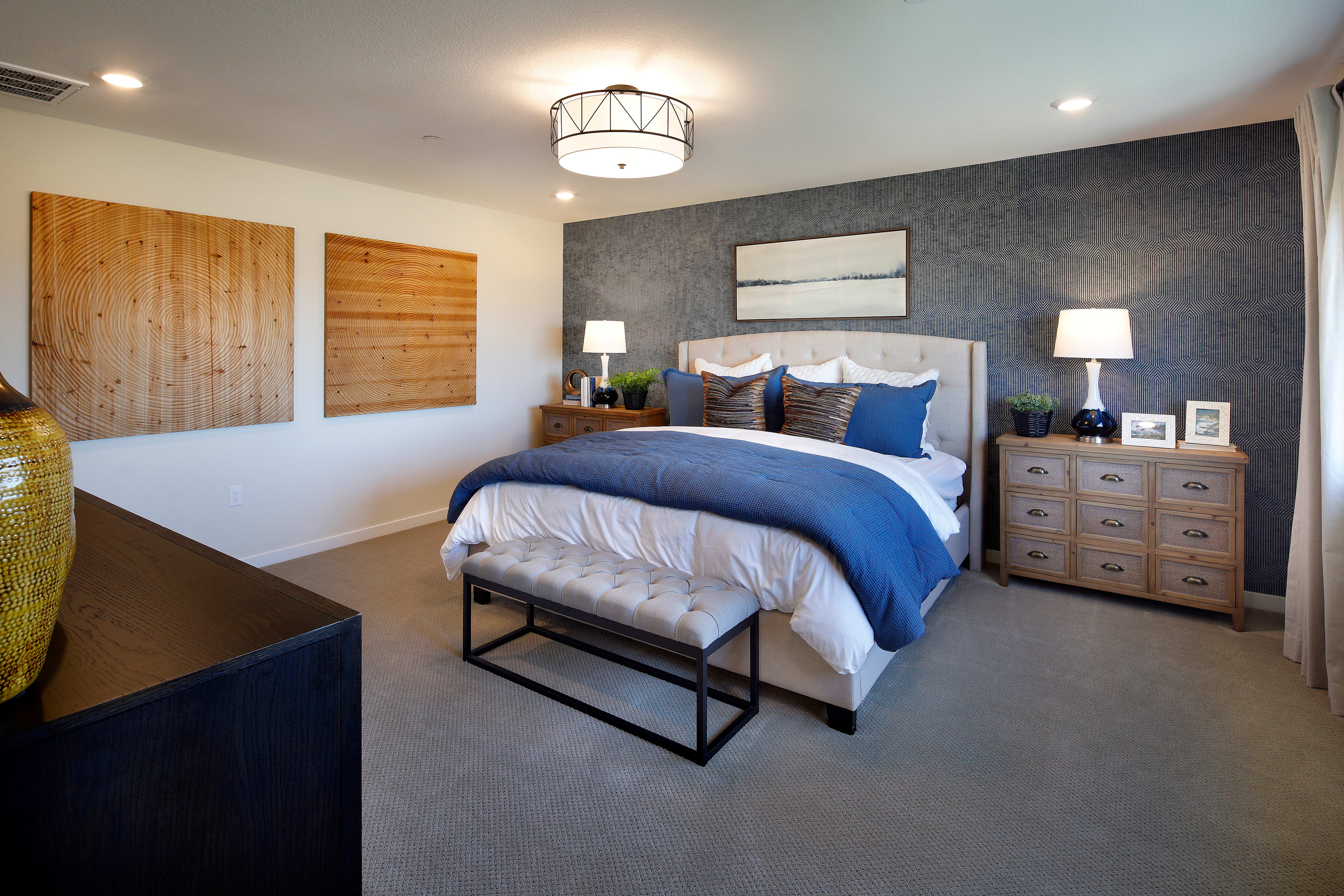 A cozy and modern bedroom with a plush bed, wooden accents, and a stylish chandelier overhead, creating a warm and inviting atmosphere.