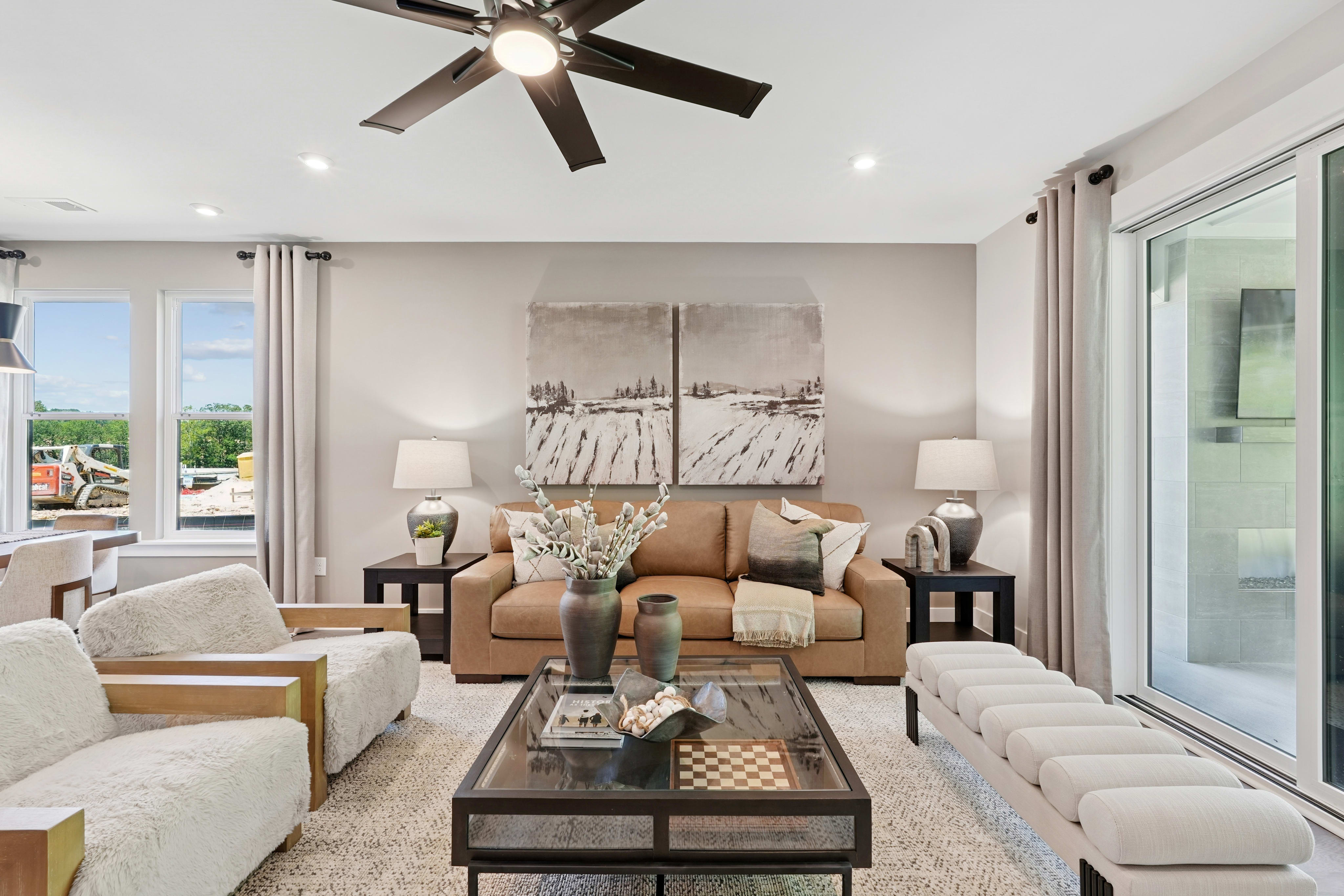 A cozy and well-furnished living room with a large window overlooking a scenic outdoor view, featuring a comfortable sofa, armchair, and a coffee table with decorative elements.