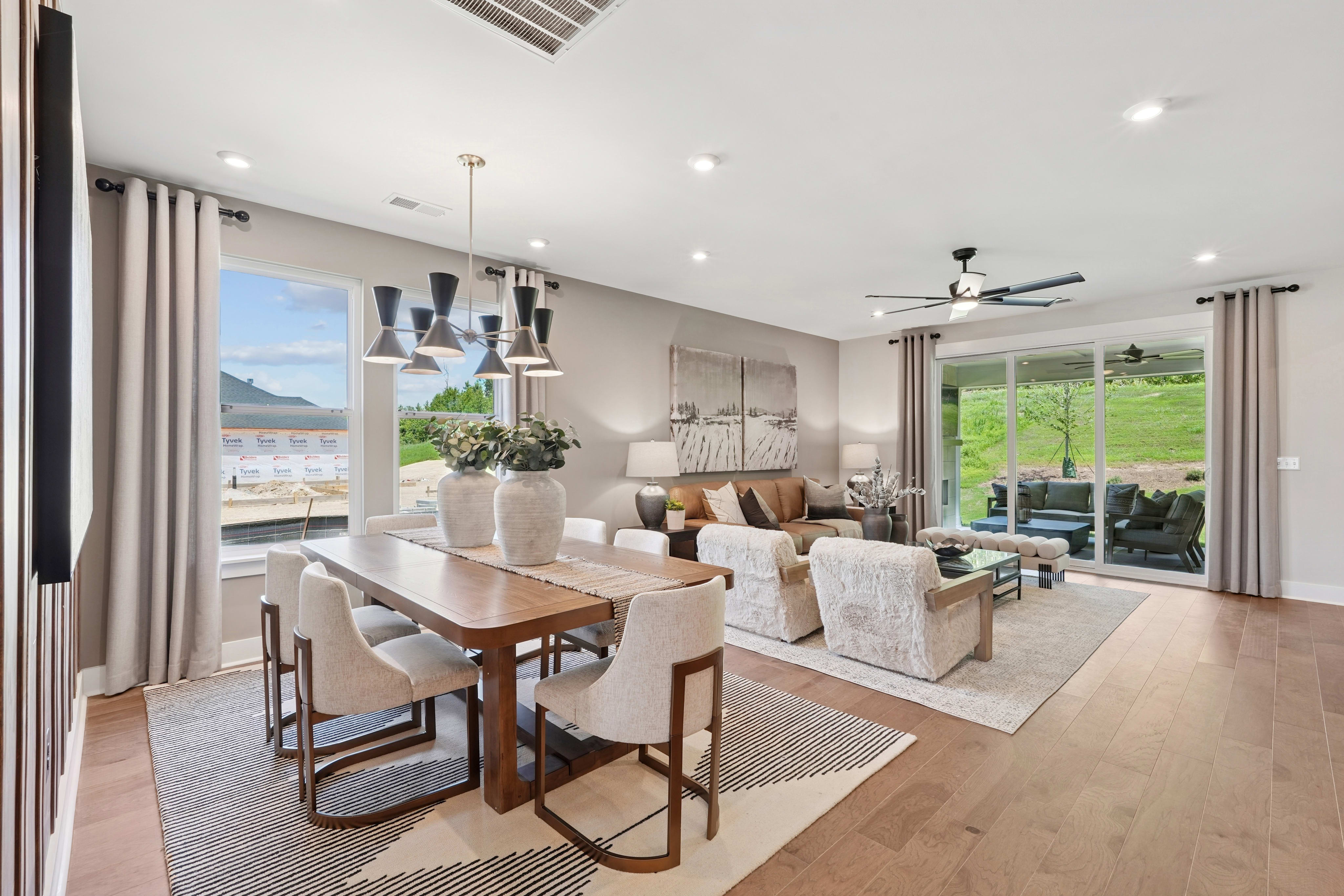 A spacious and well-designed open-concept living and dining area with large windows offering a scenic view of the surrounding landscape.