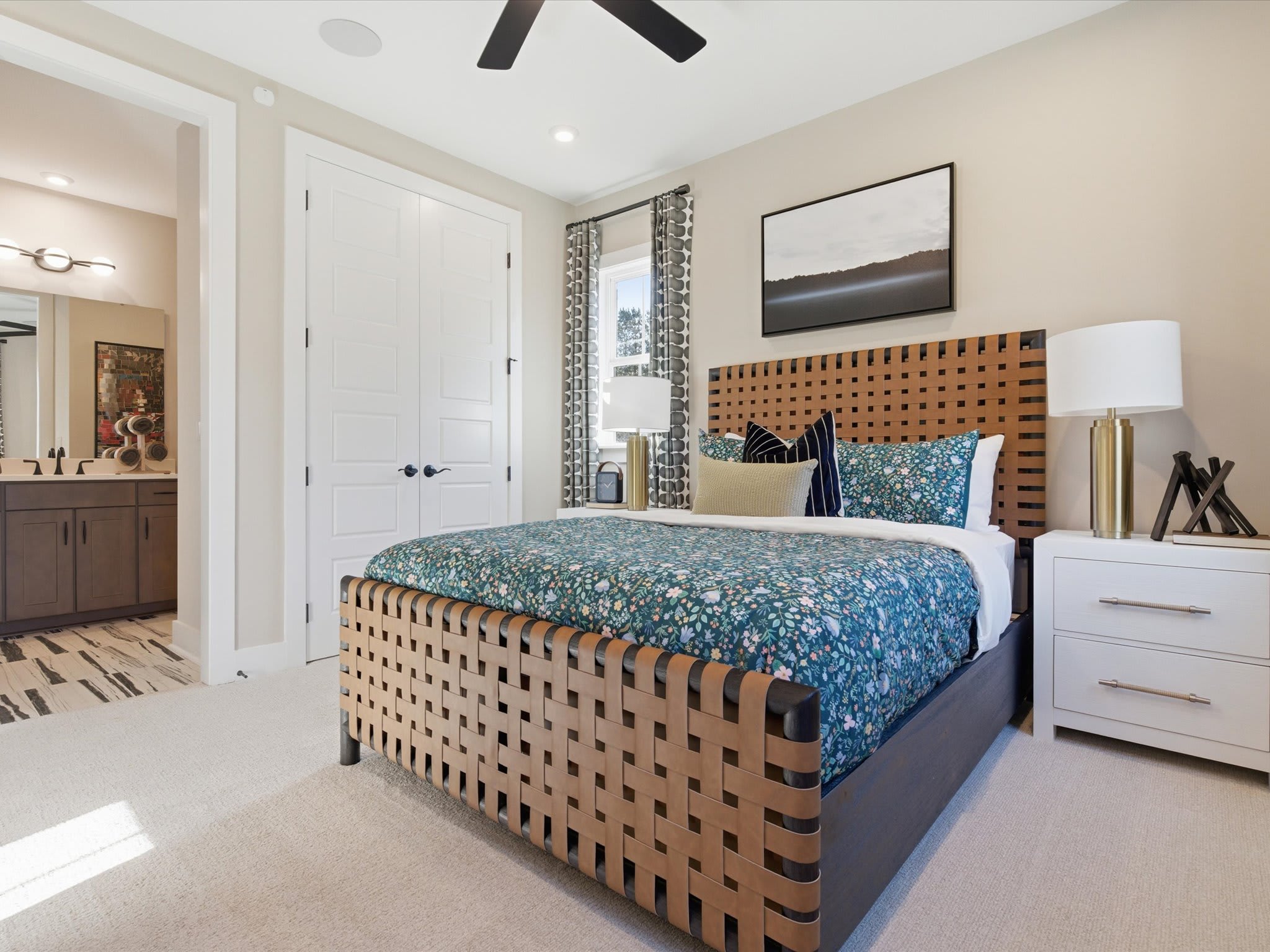 A cozy and modern bedroom with a wooden slatted bed frame, a patterned bedspread, and various decorative elements such as artwork and lamps.