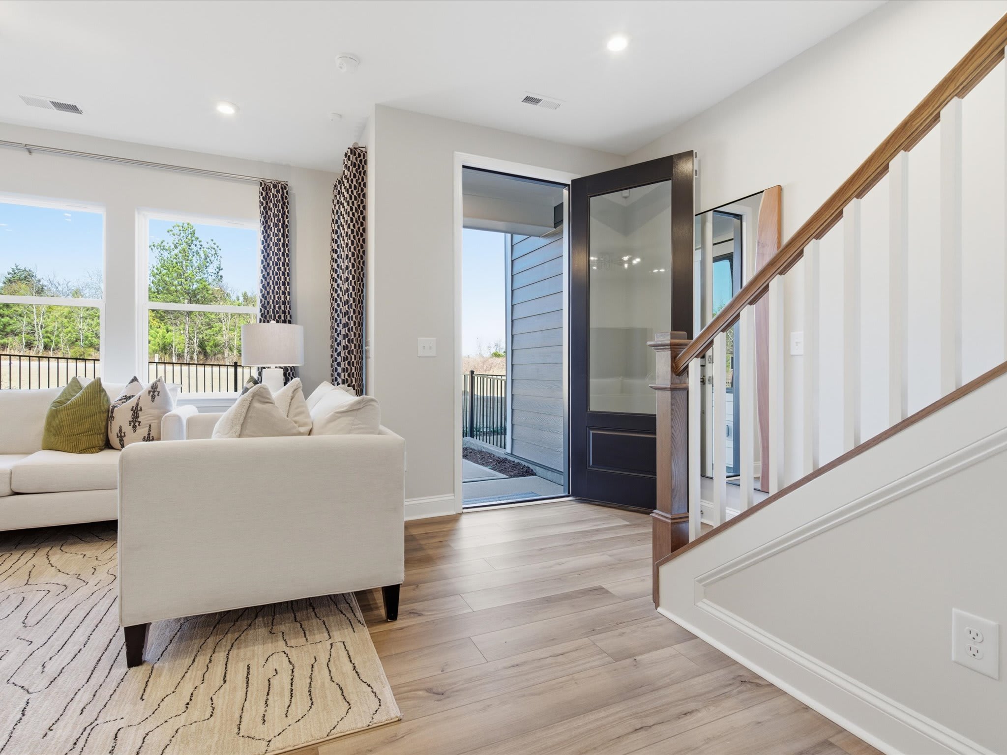A modern and bright living room with a comfortable sofa, wooden floors, and a glass door leading to an outdoor area.