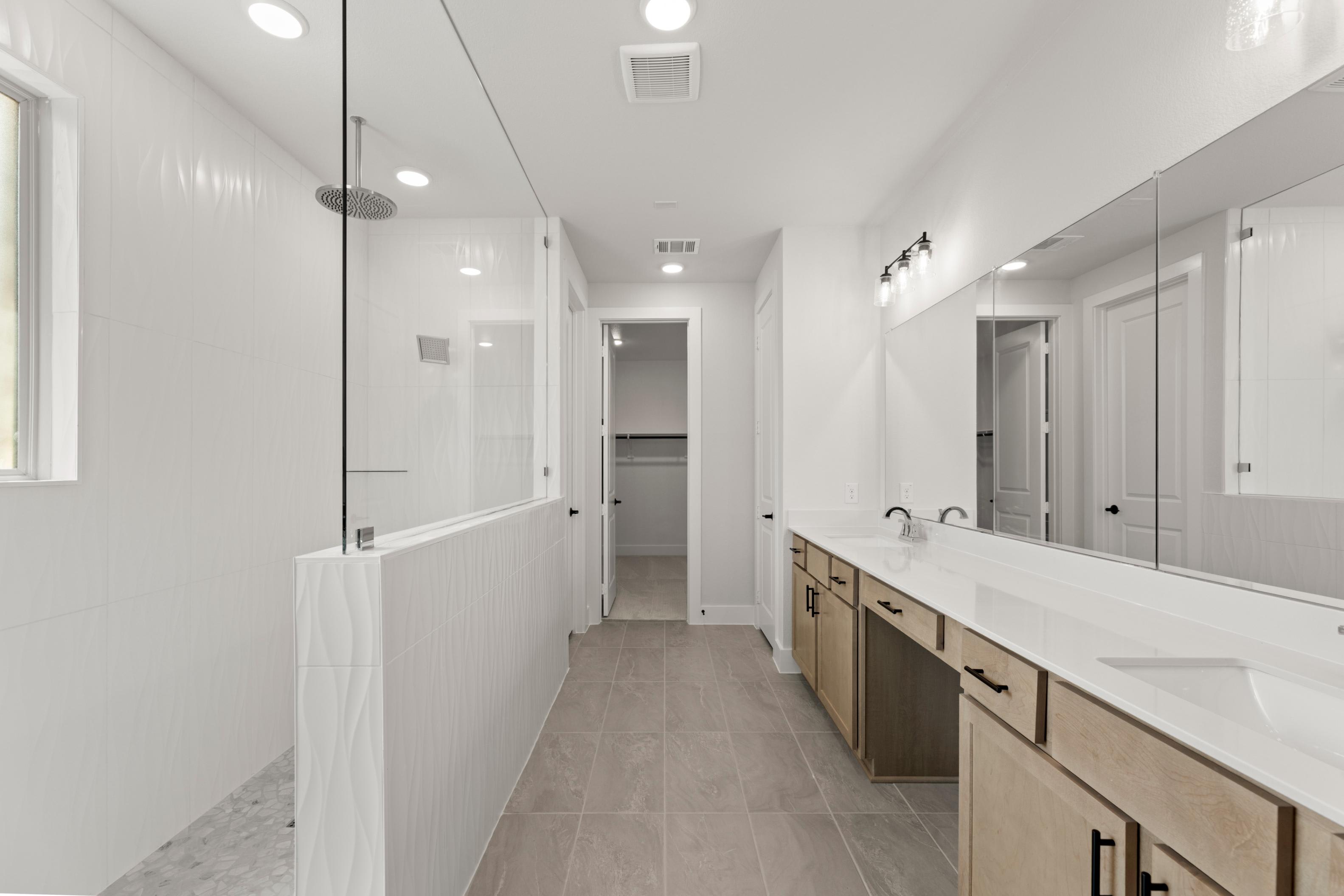 A long, narrow hallway with white walls, a tiled floor, and a vanity with drawers and cabinets along one side.