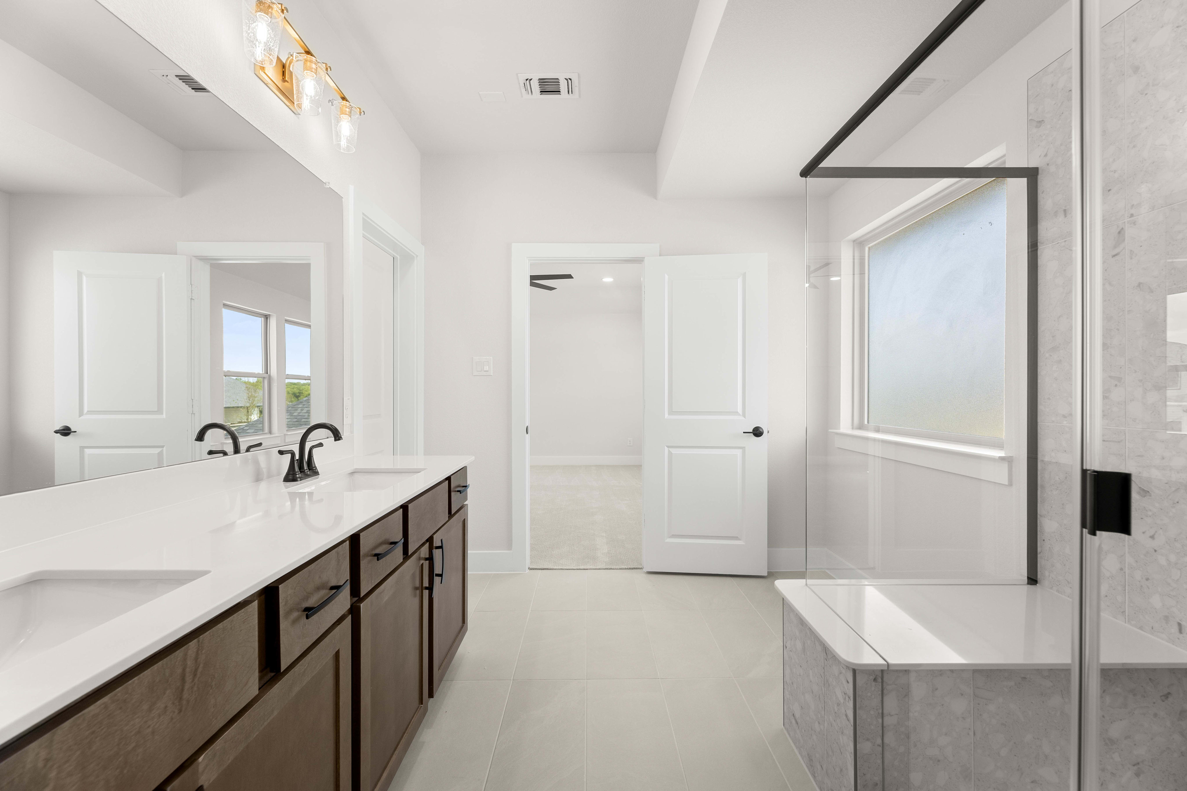 A modern, minimalist bathroom with a large vanity, white walls, and a window providing natural light.