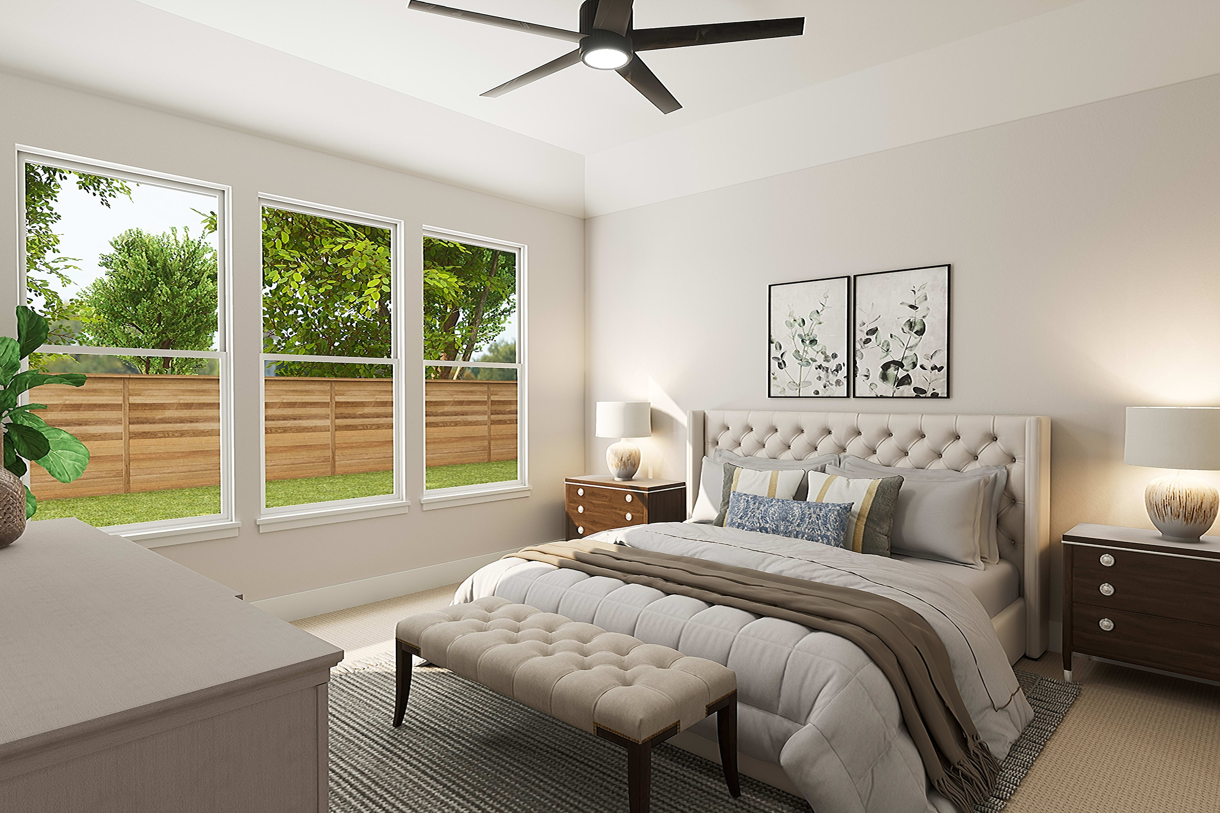 A cozy and well-furnished bedroom with a large window overlooking a lush, green outdoor space, featuring a plush tufted headboard, nightstands, and a ceiling fan.