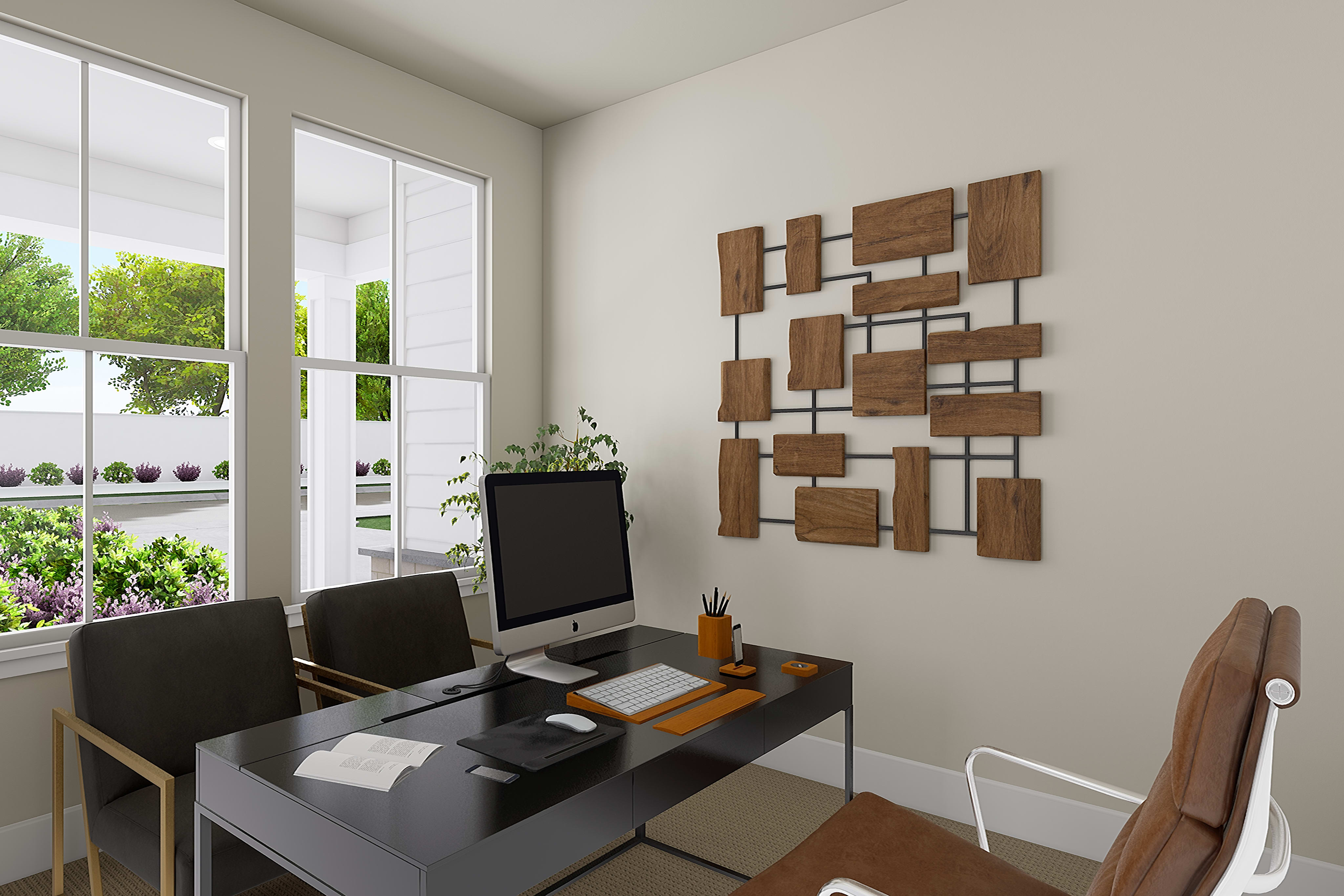 A modern and minimalist home office space with large windows overlooking a lush, green outdoor landscape, featuring a wooden wall art piece and a simple desk setup.